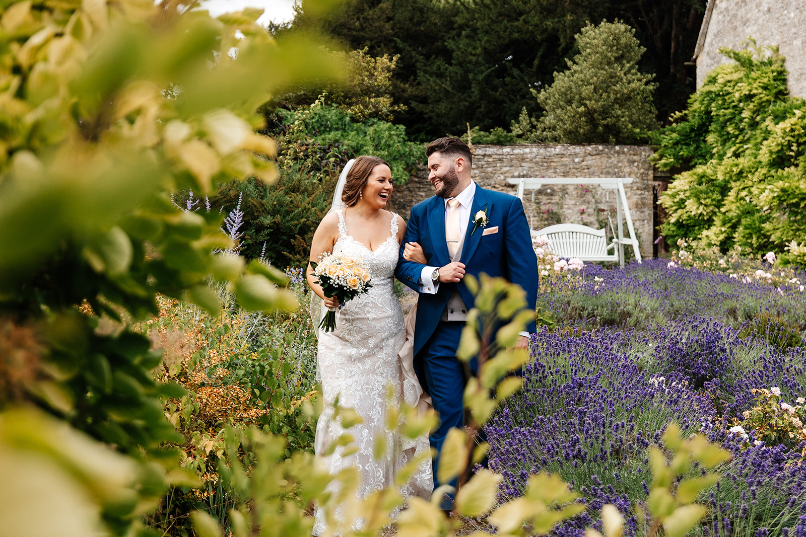 Couple take a walk through Caswell House grounds surrounded by lavender, wildflowers and greenery 