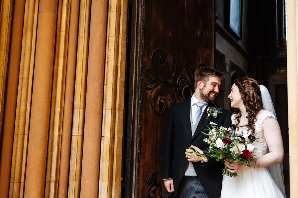 A married couple standing infront of a chapel on their wedding day