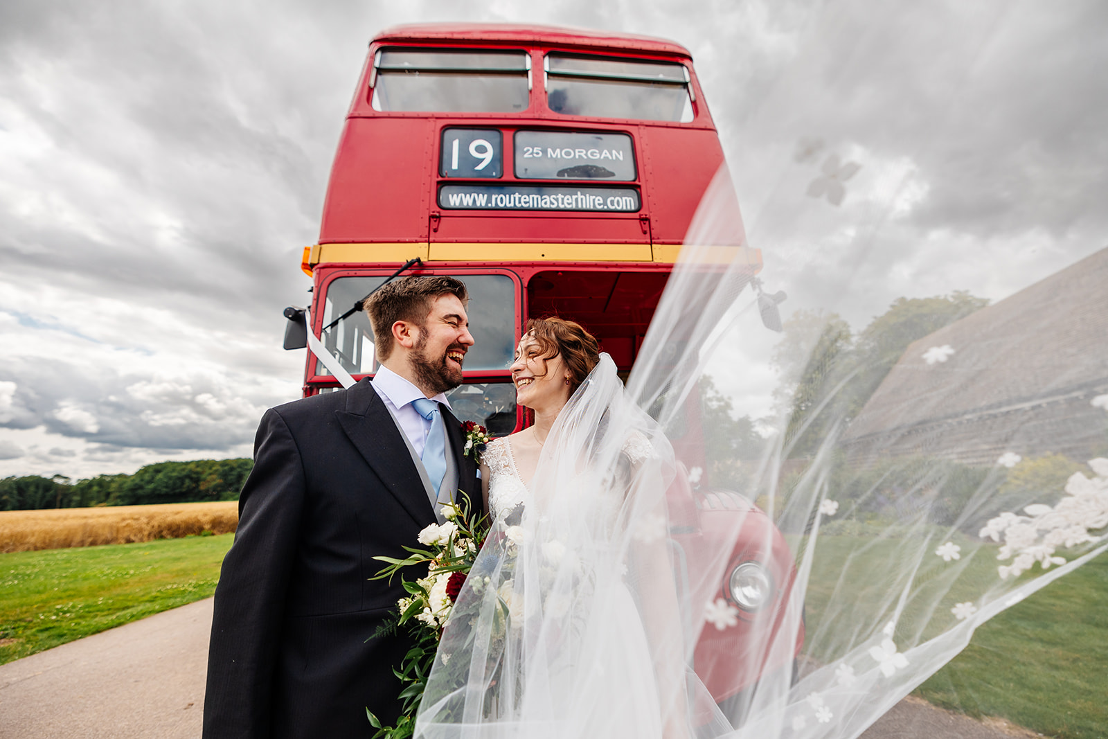 a married couple infront of a double decker bus