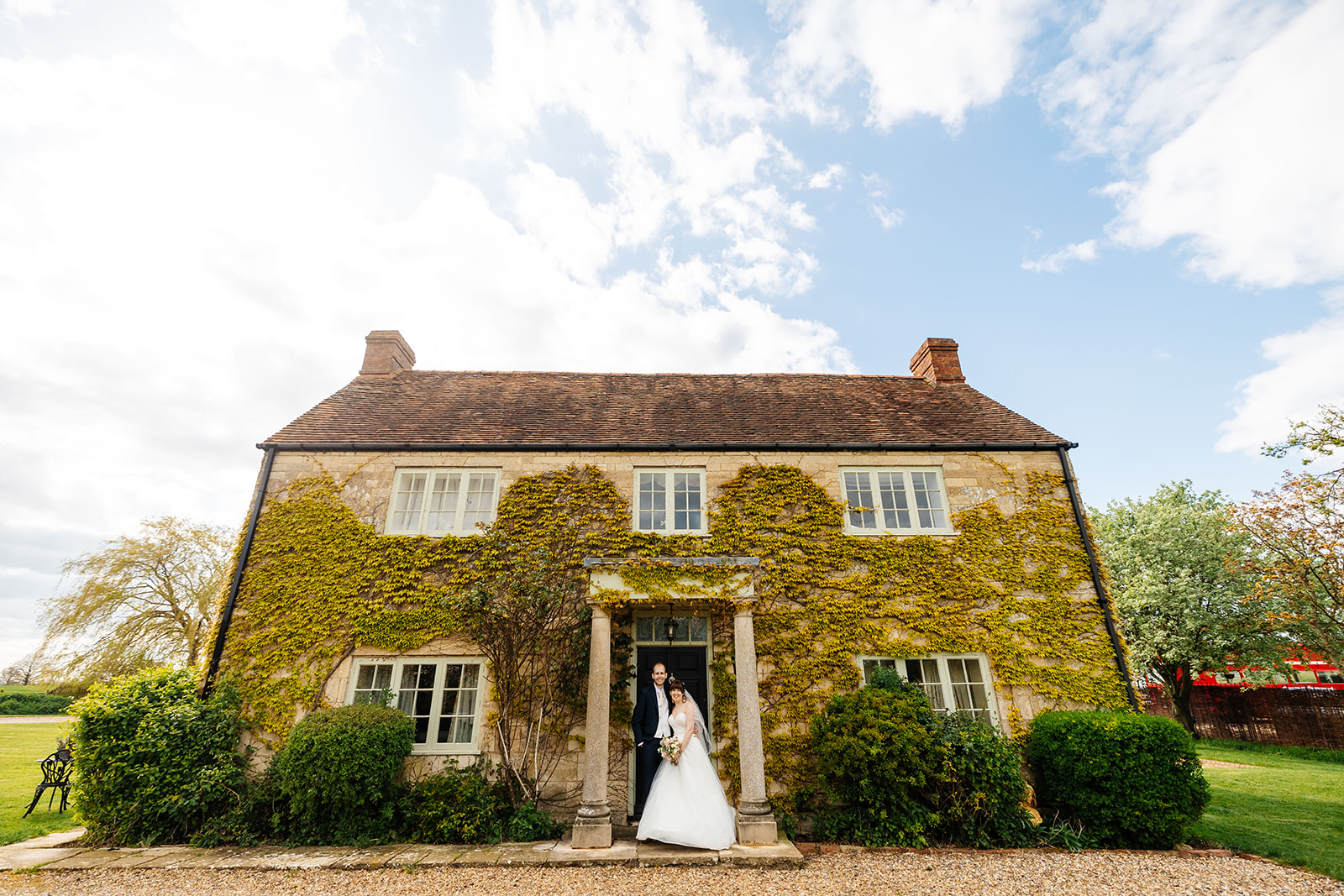 The newlyweds standing in a doorway of an old house covered in green ivy