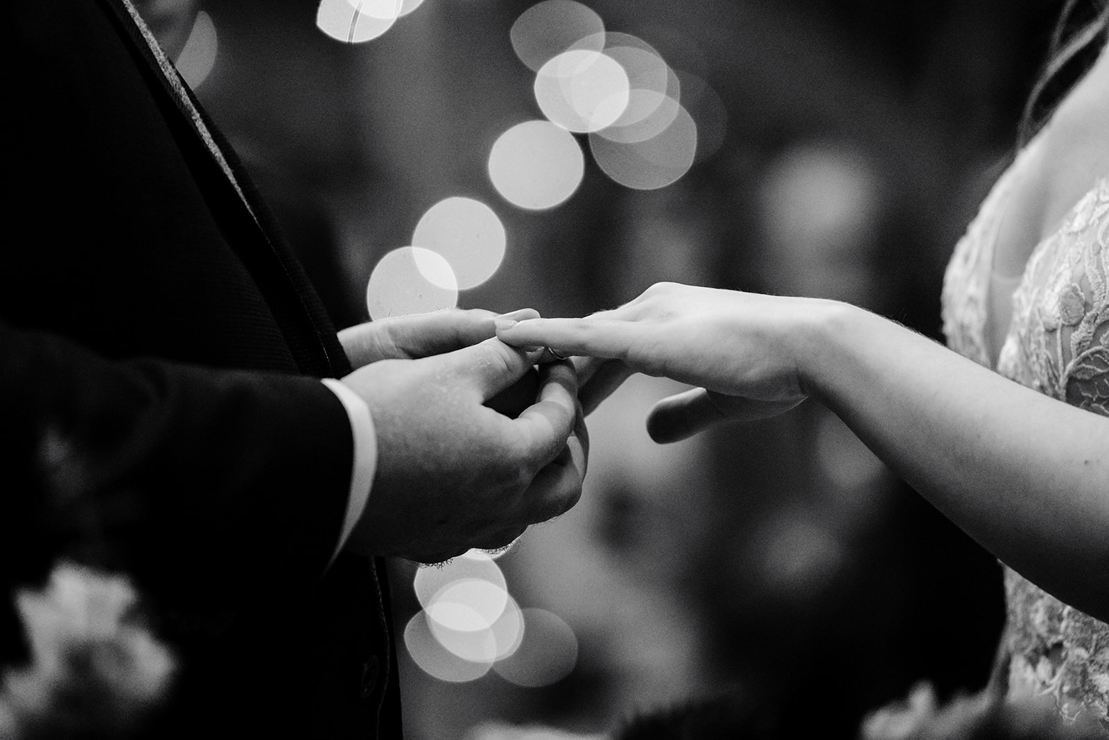 A bride and groom's hands as the groom puts the ring on his new wife