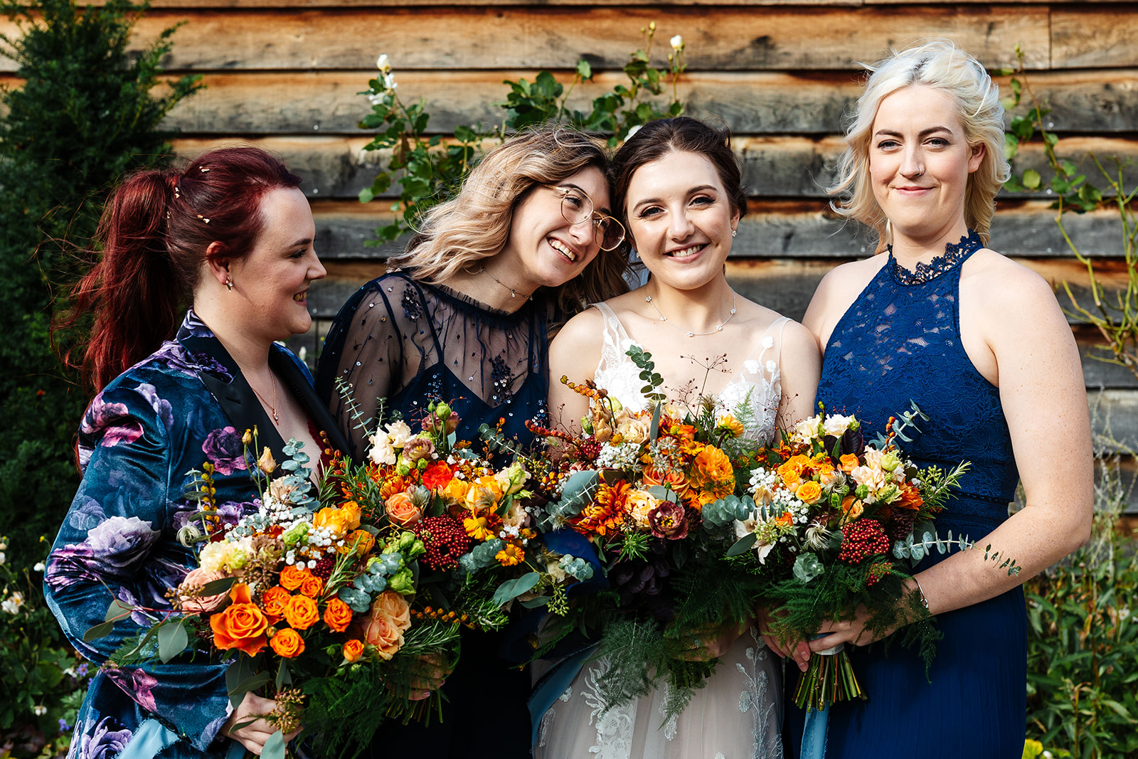 A bride and her bridesmaids holding their flowers and smiling