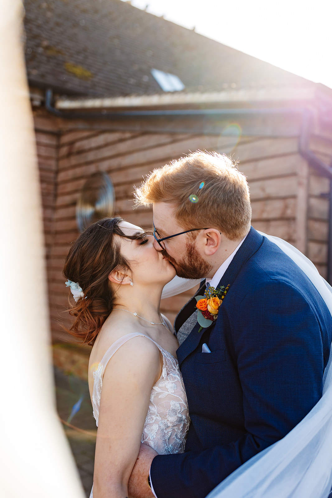 The bride and groom kissing outside with the sun glowing on them