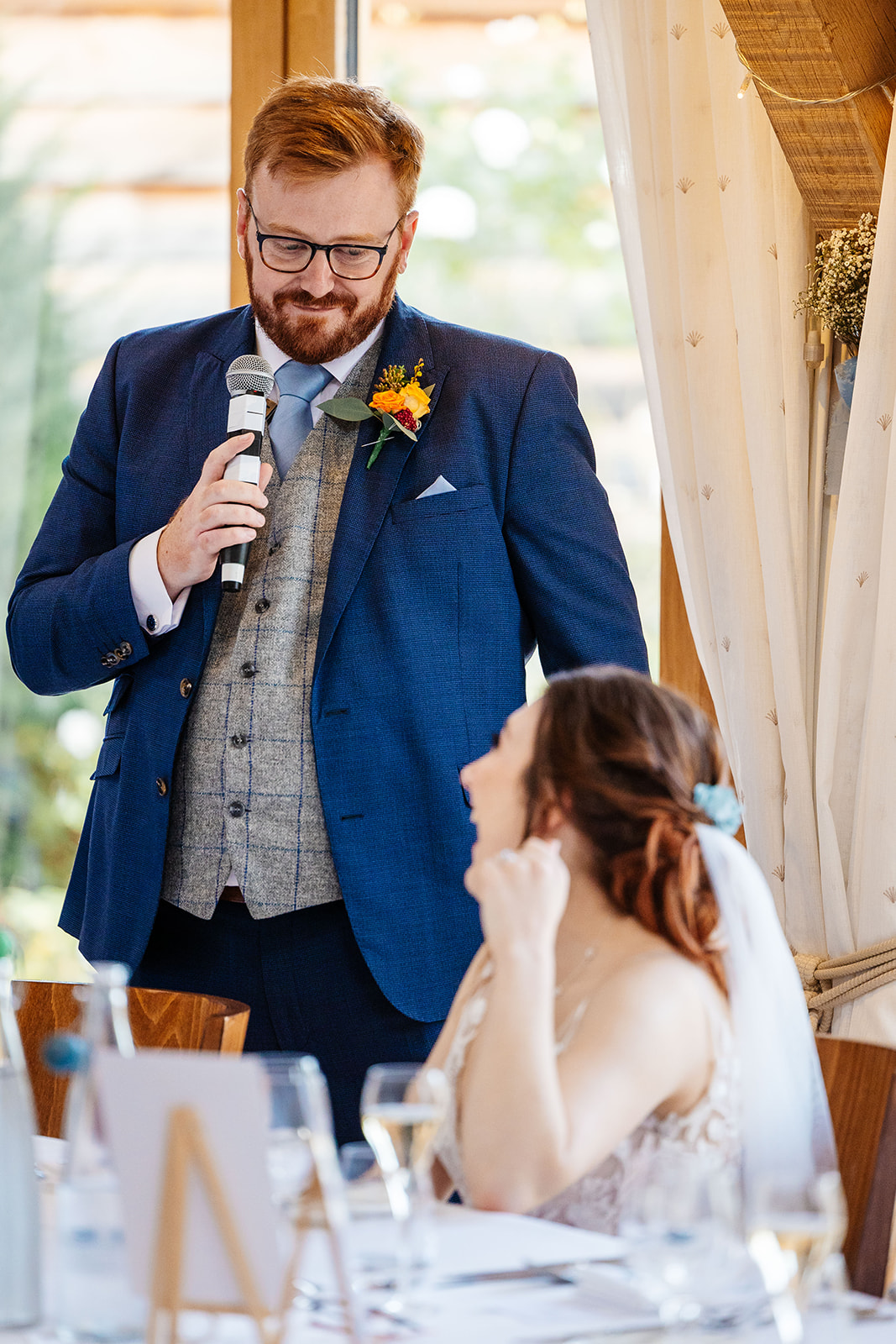 The groom looking at his new wife with a microphone in his hand giving a speech