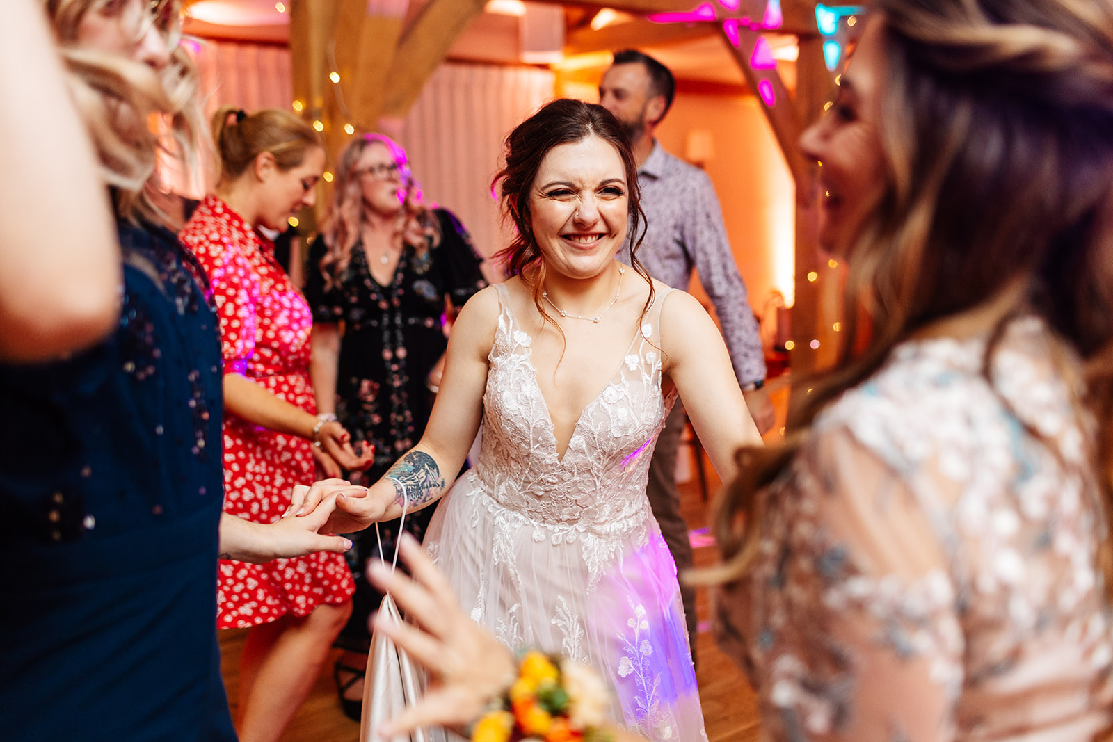 The bride on the dance floor in a sleeveless dress smiling happily