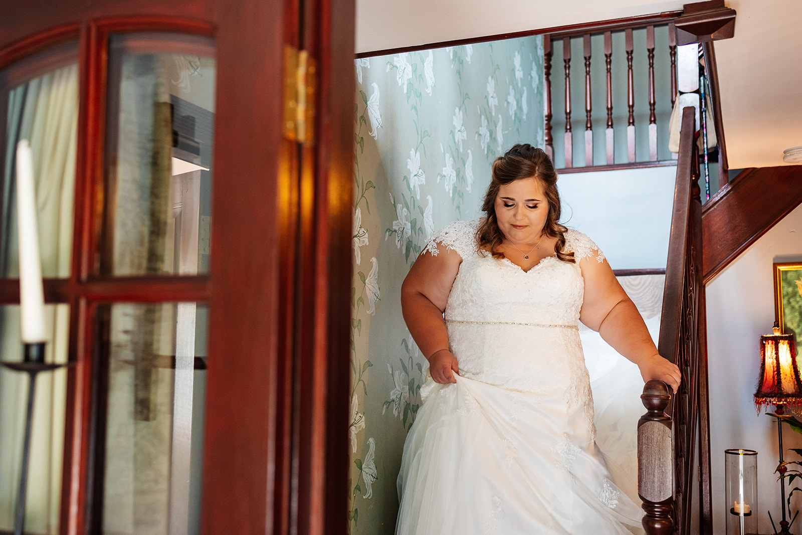 A bride in a white dress walking down the stairs as she gets ready for her wedding
