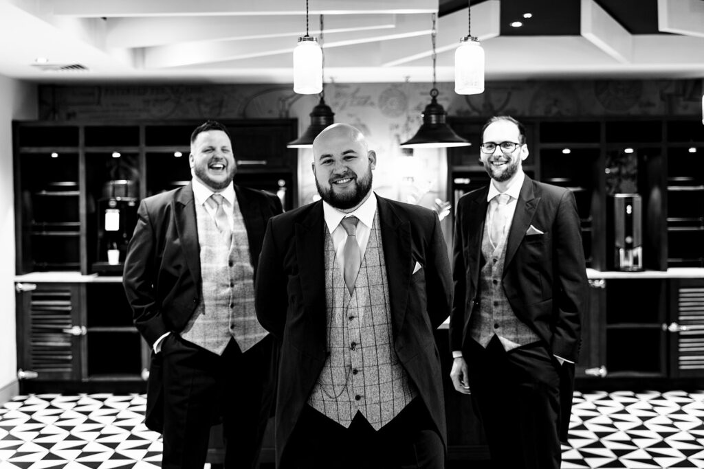 A groom and his best men waiting in an indoor space ready for his wedding in black and white
