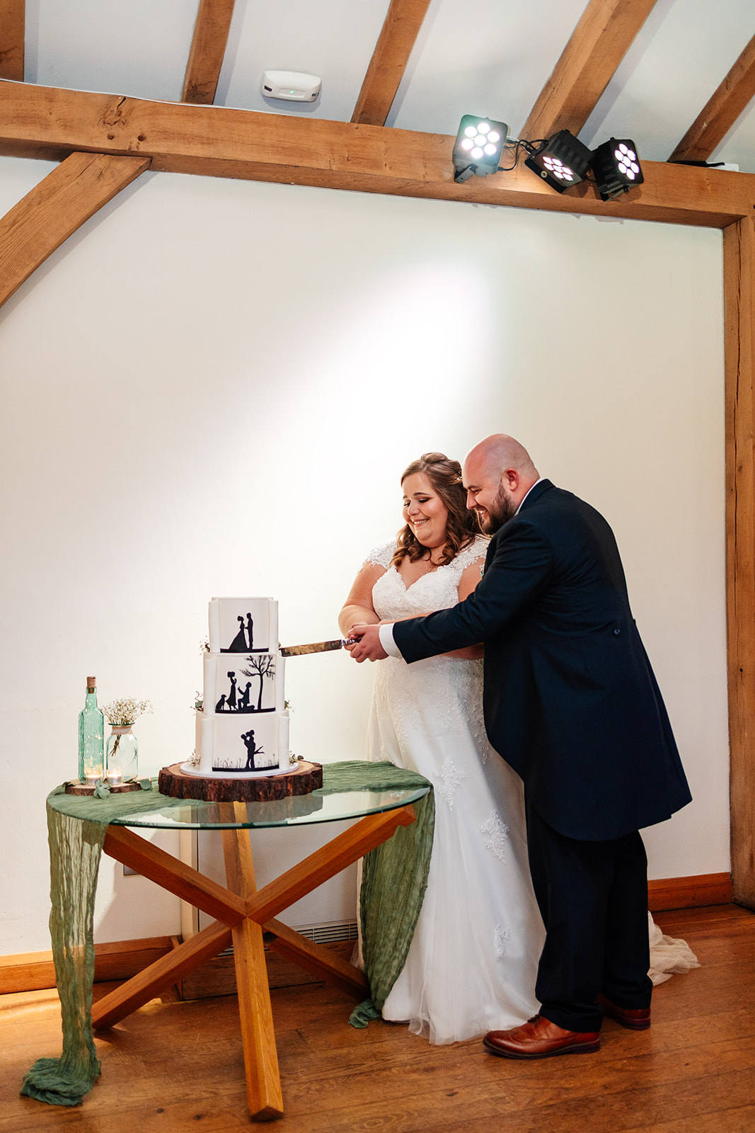 A bride and groom cutting their three tiered cake