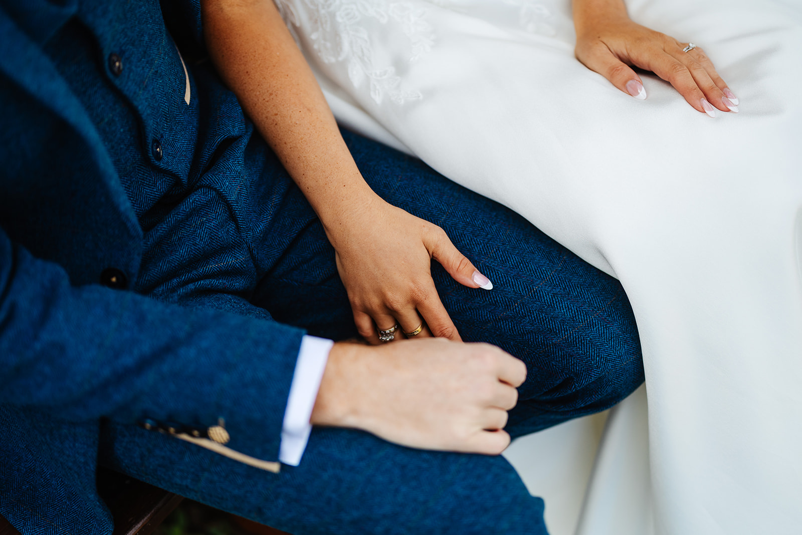 A wives hand on her husbands knee showing off her wedding ring 