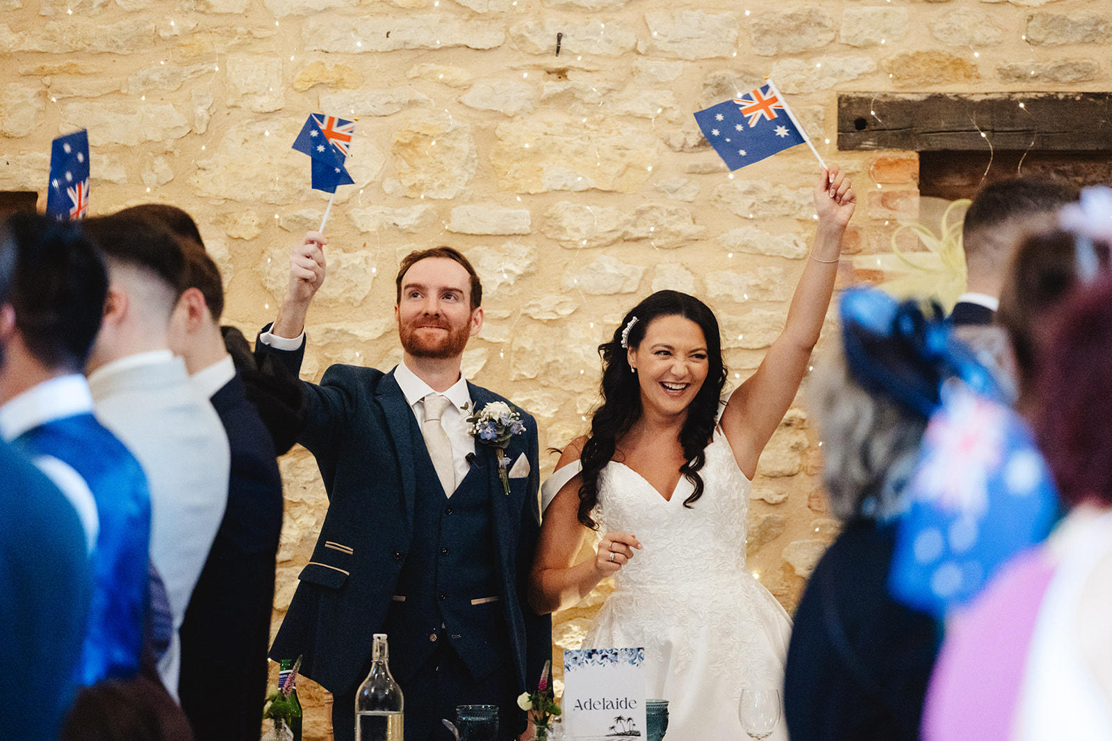 A bride and groom waving a mini australian flag around in the air, celebrating