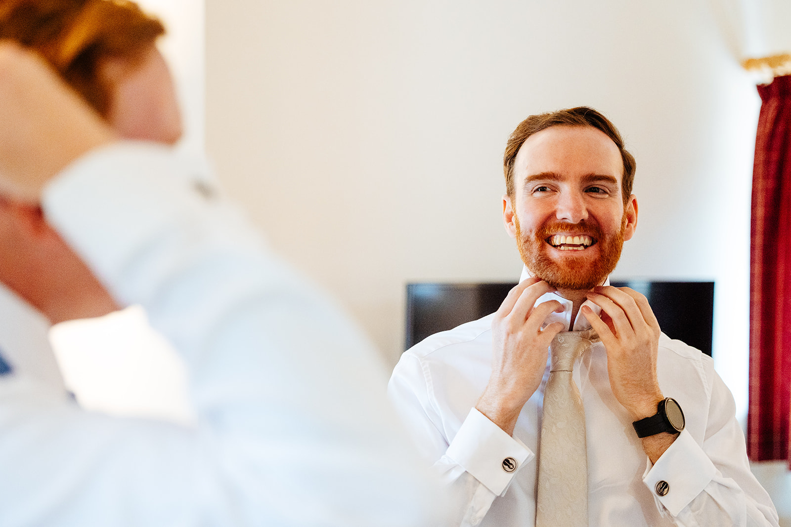 A groom putting his white tie on on his wedding day