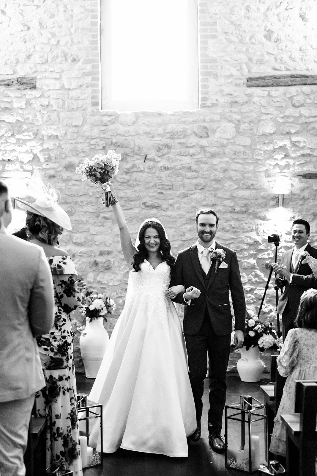 A black and white image of a bride and groom walking down the aisle after they are married