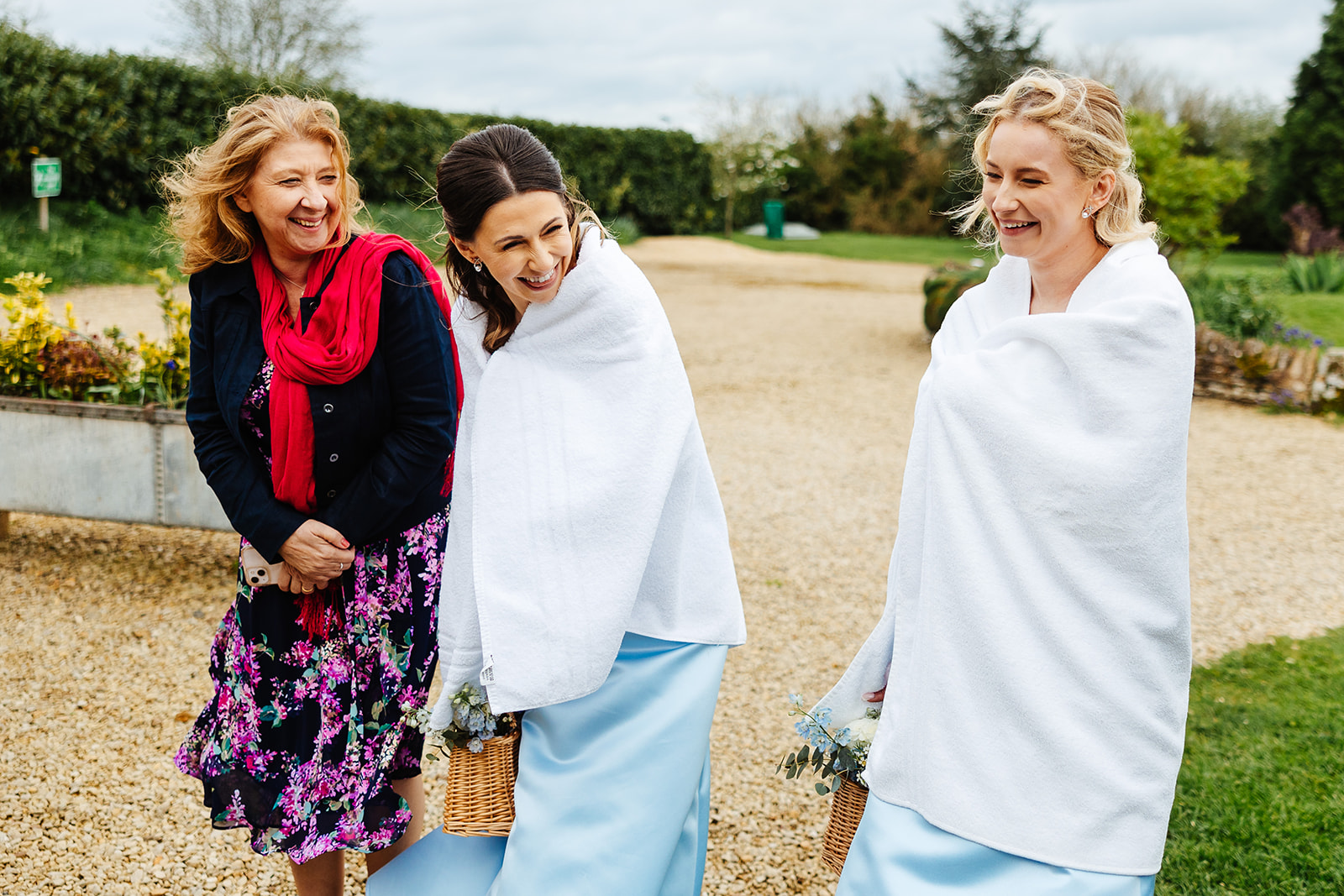 Two bridesmaids dressed in baby blue dresses with white blankets around their shoulders, smiling