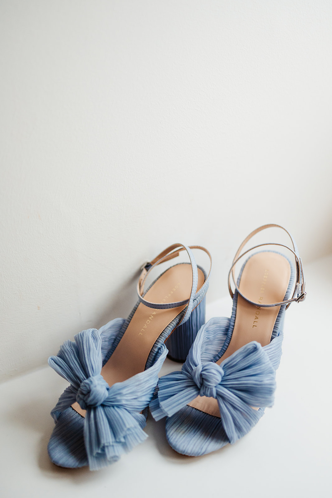 A powder blue pair of heels with a ribbon bow on the front