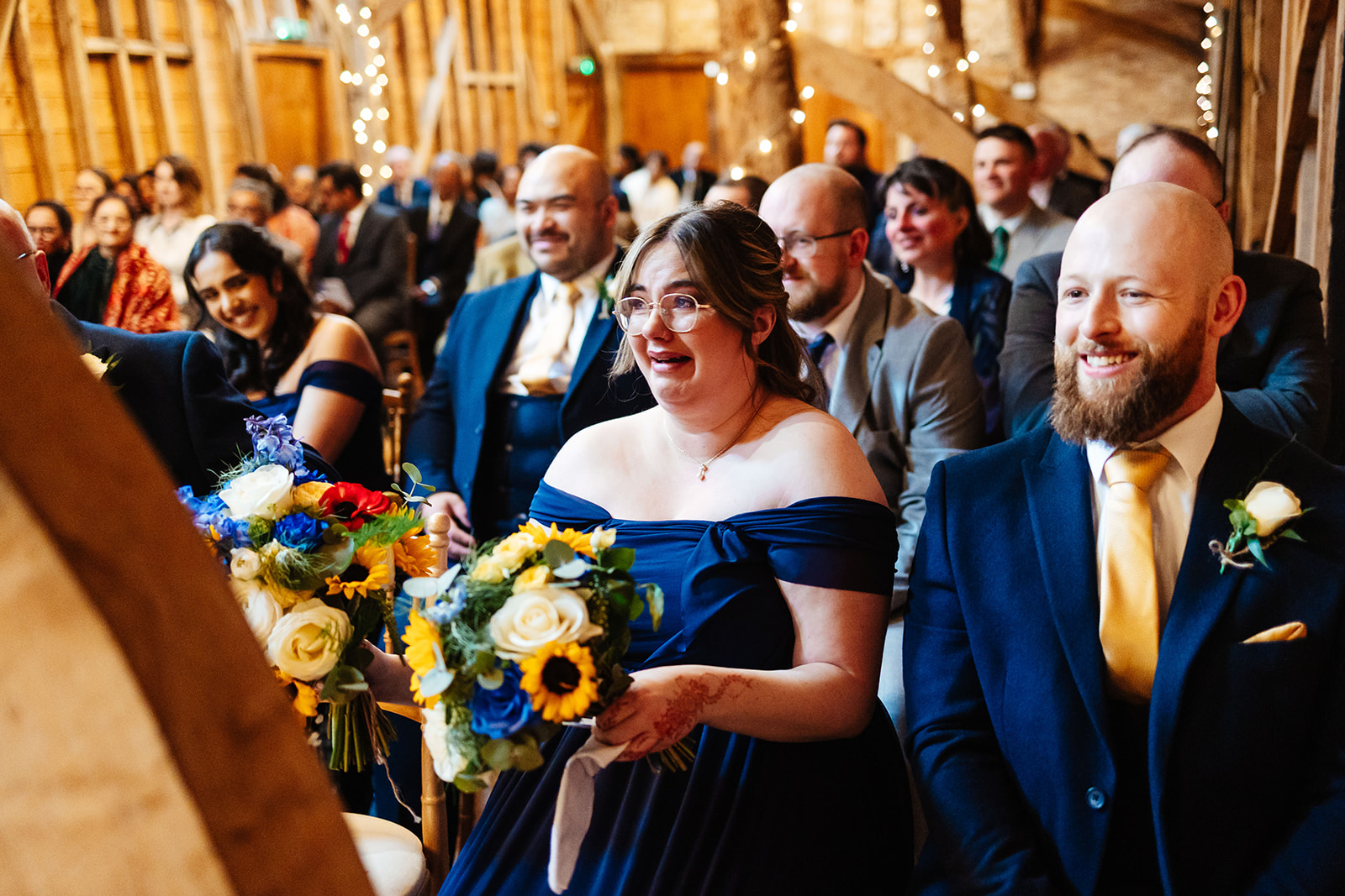 A bridesmaid dressed in navy blue crying happy tears