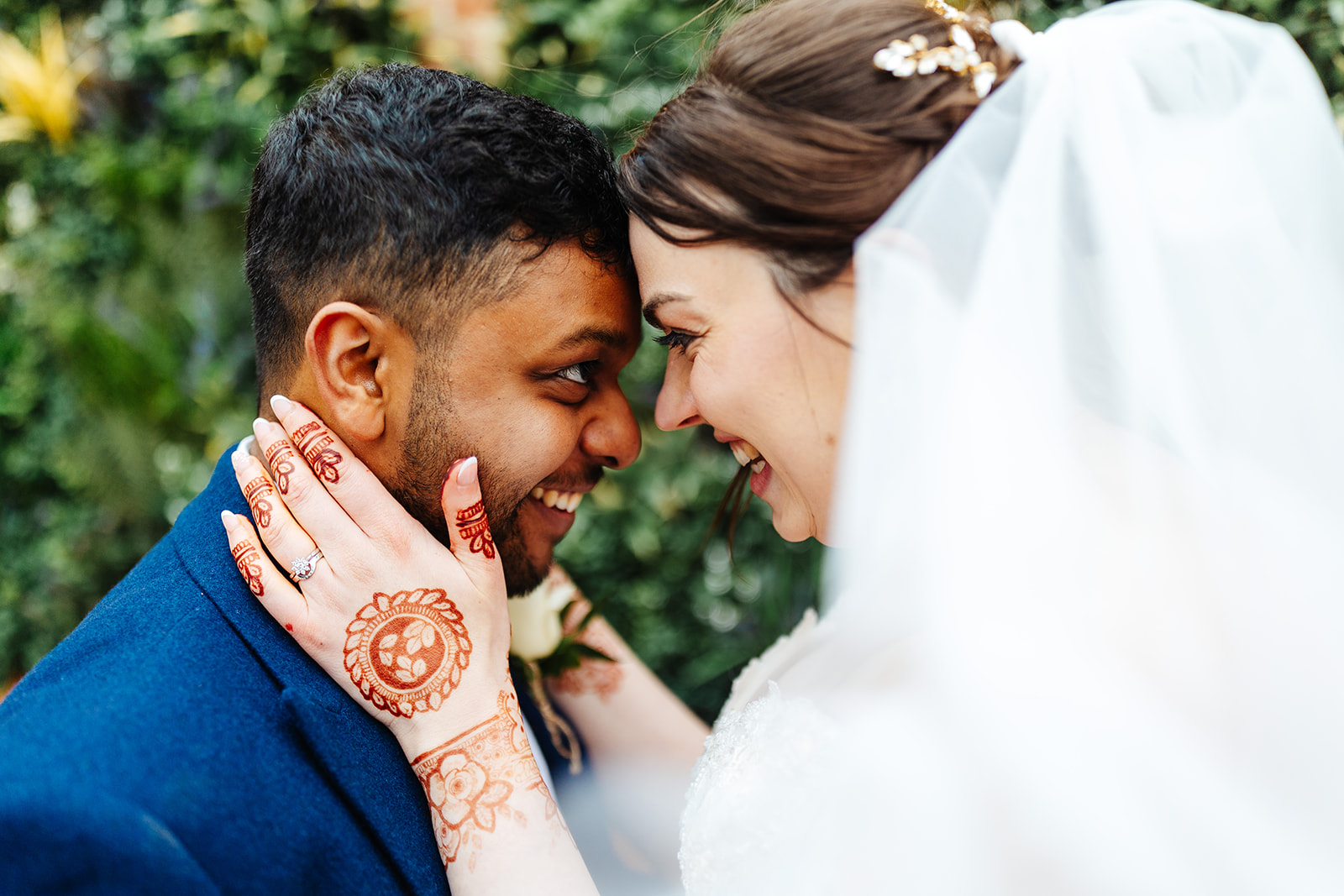 A married couple looking lovingly into each others eyes. The bride has her hands which are covered in beautiful henna tattoo designs, are holding on to the groom's face
