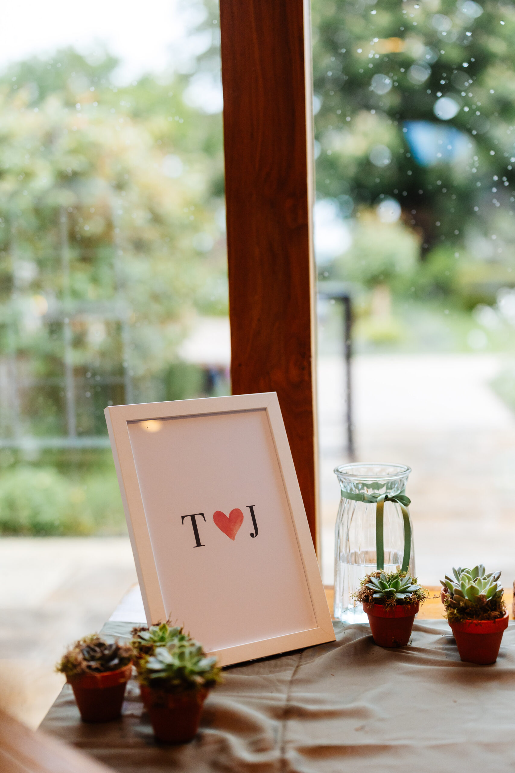 A white wooden frame with T and a love heart and J on it.