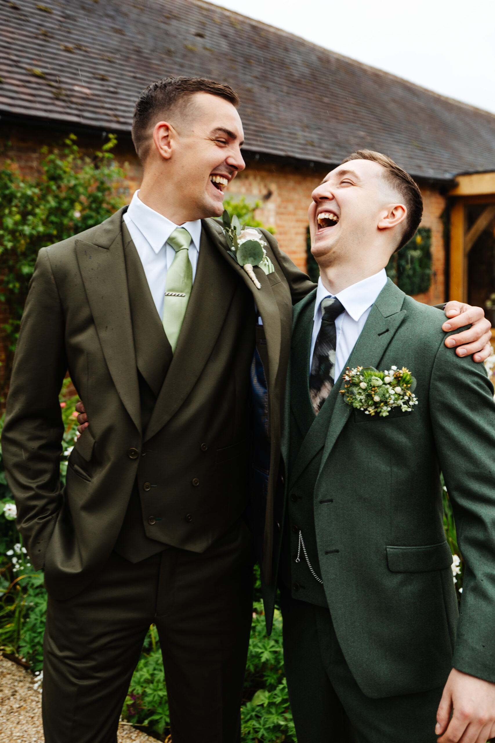 Two men in green suits looking at each other and smiling.