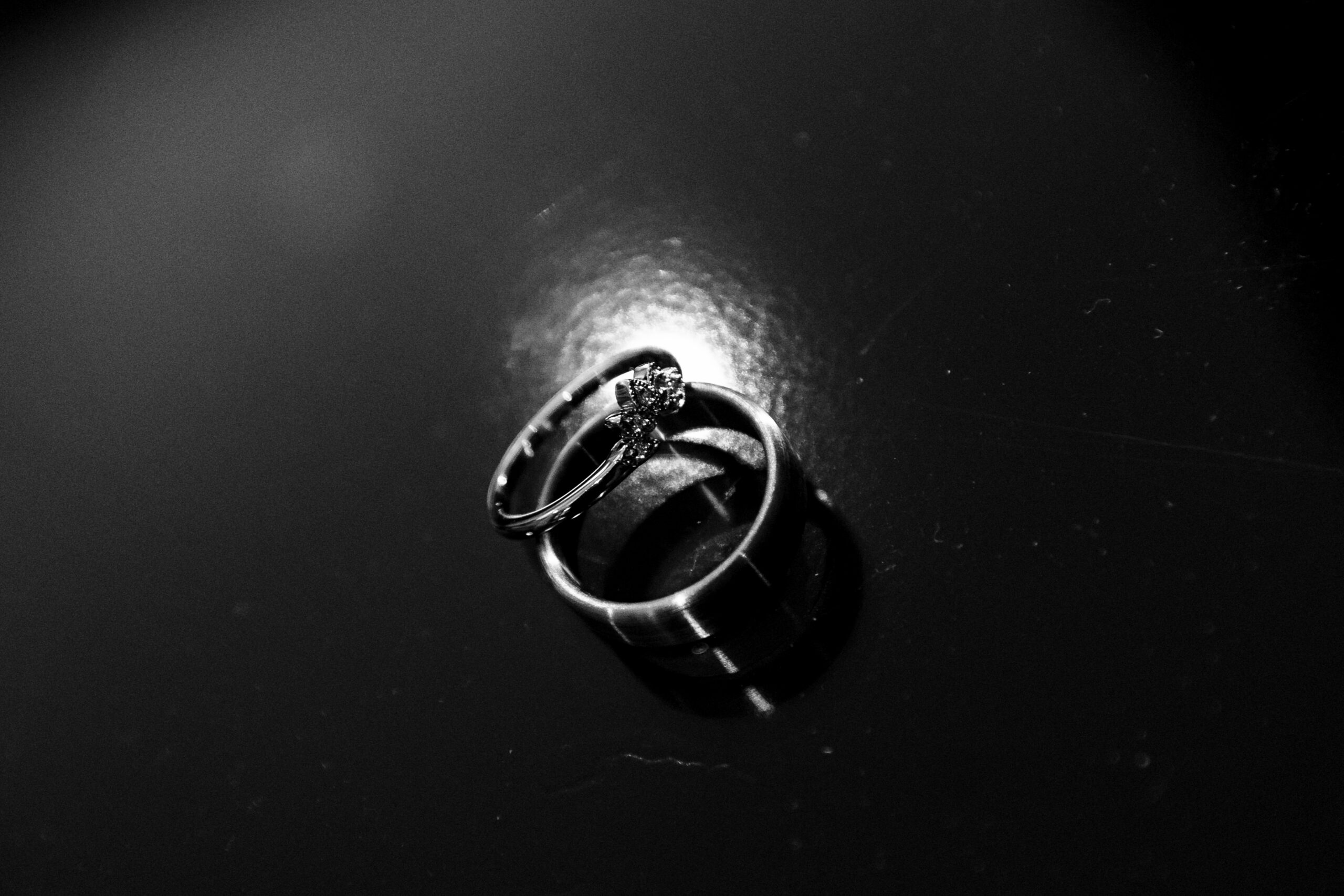 A black and white image of an engagement ring and a wedding band.