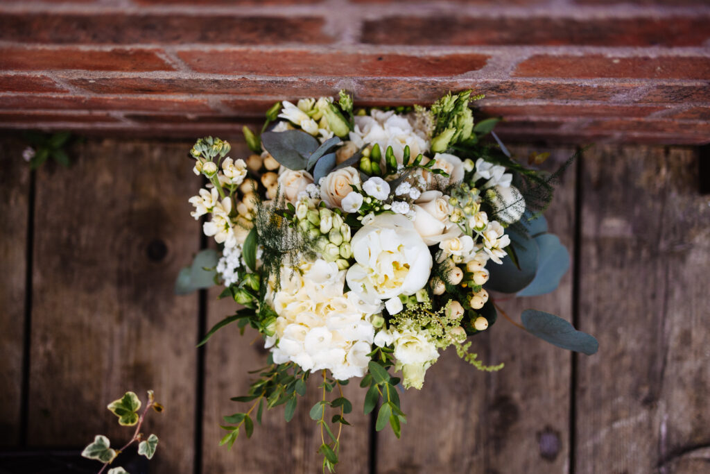 A photo of a bouquet of white flowers with greenery dotted in them including eucalyptus. 