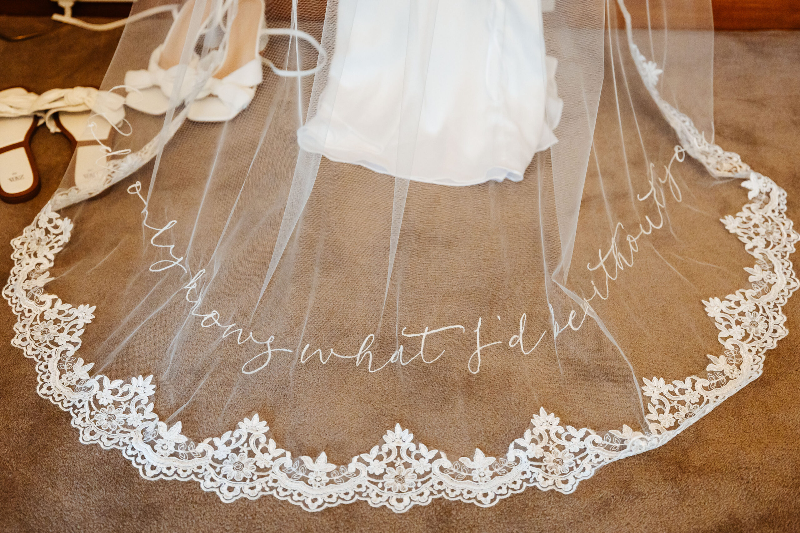 A veil spread out on the floor with the words "God only knows what I'd be without you" embroidered on it in white calligraphy style writing.