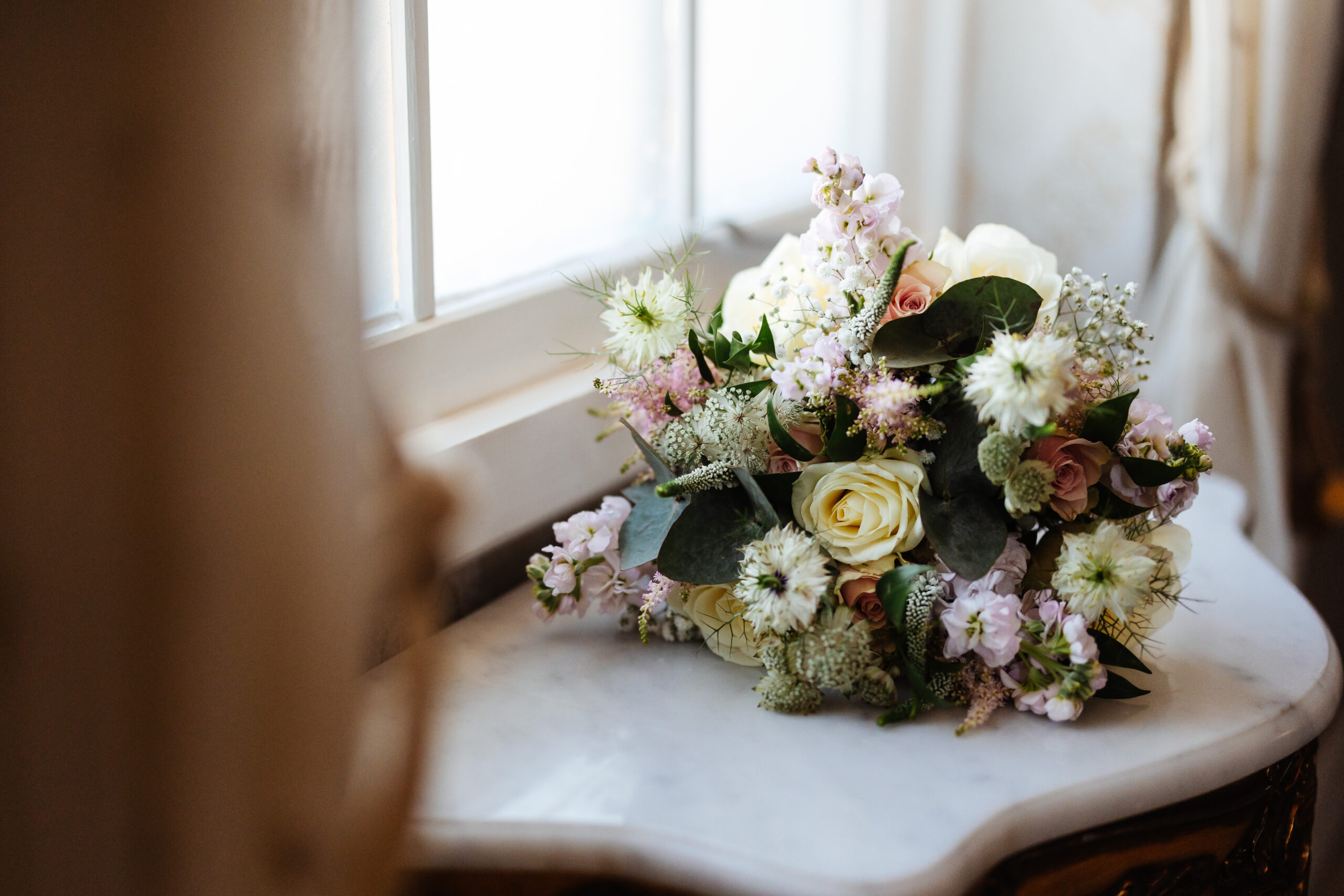 A bunch of wedding flowers on the side. They are a beautiful bunch containing white roses, pink flowers and eucalyptus. 