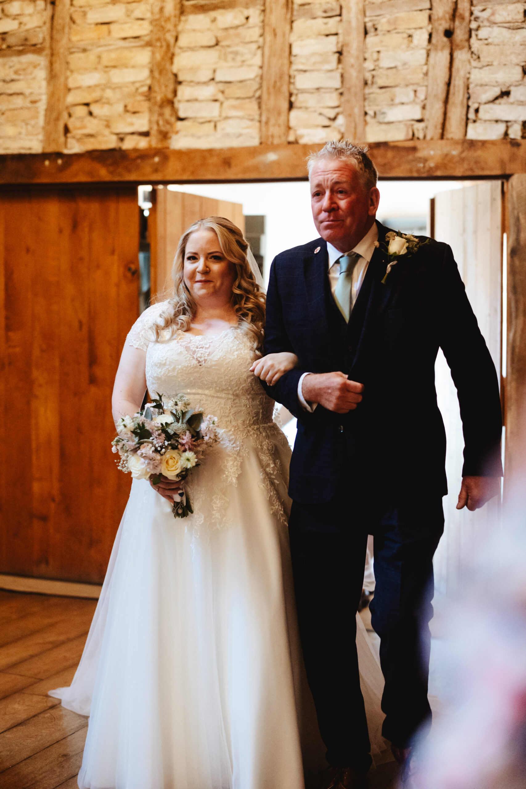 The bride and her father walking down the aisle. They both look a little nervous and emotional. 