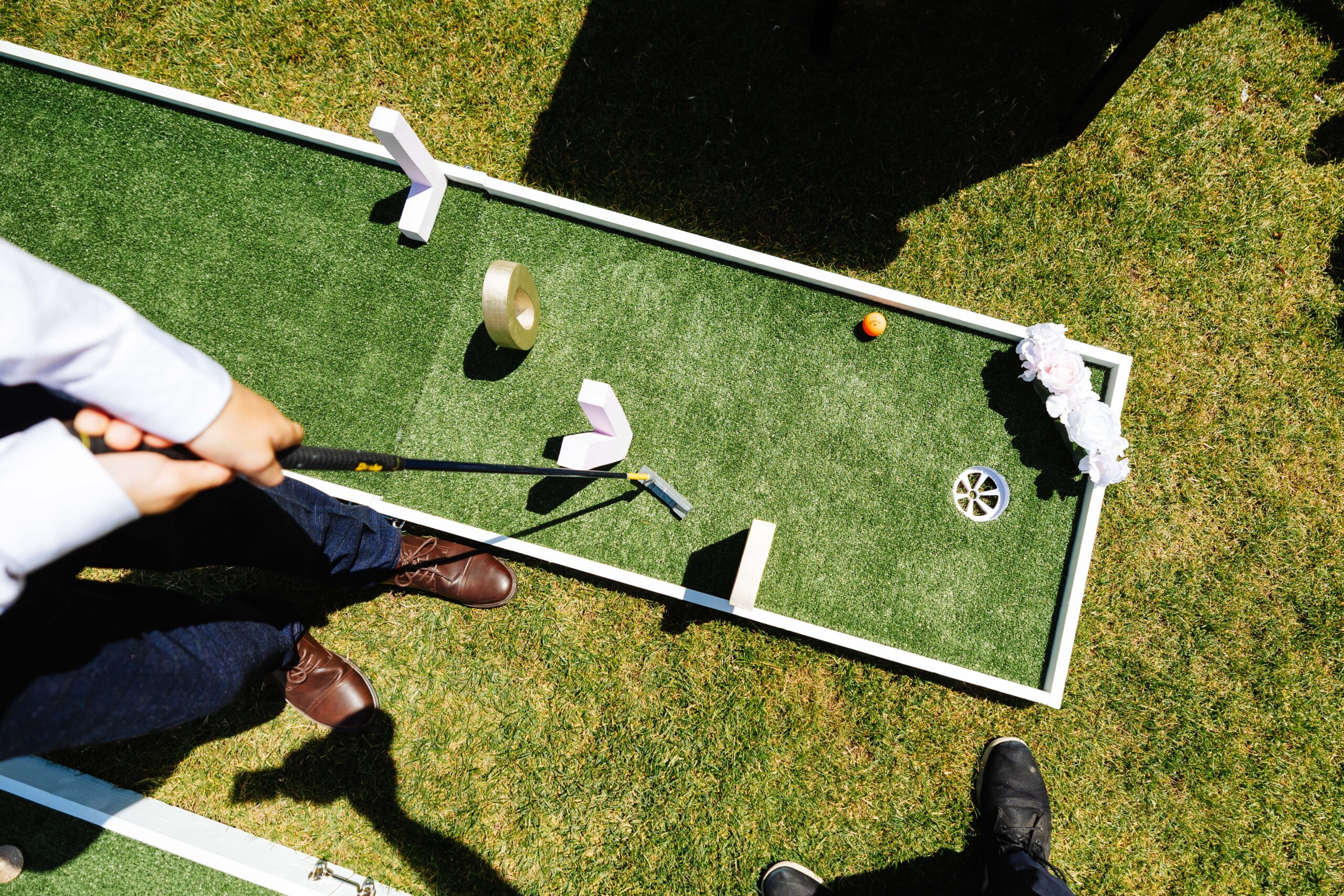 A top down image of someone playing mini golf outside. The obstacles to get through are the letters L O V E.