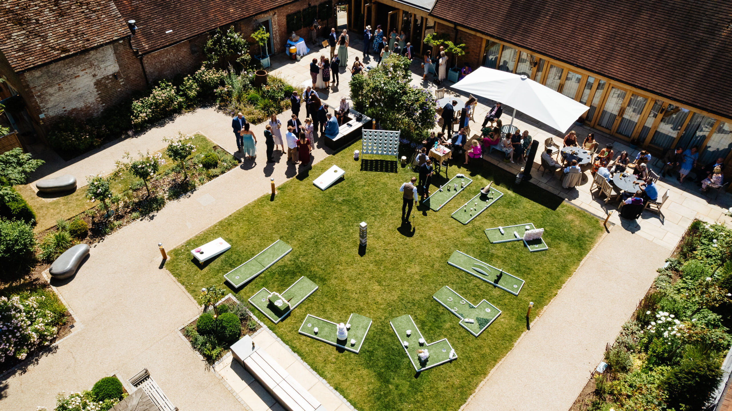 An aerial shot of outside. You can see guests mingling and having drinks as well as the mini golf in the middle of the grass area.