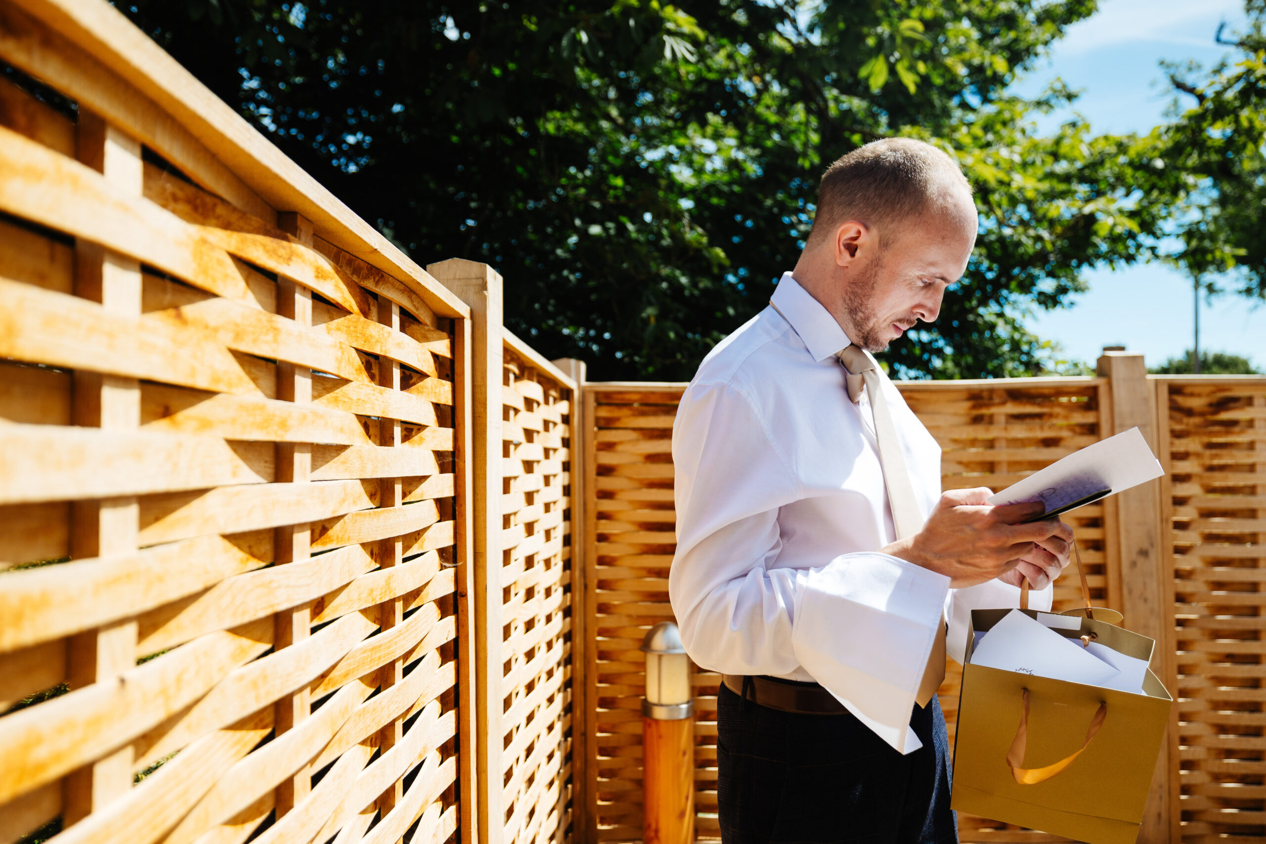 A man (the groom) outside reading a letter from his wife. His has a concentrated and emotional look on his face.