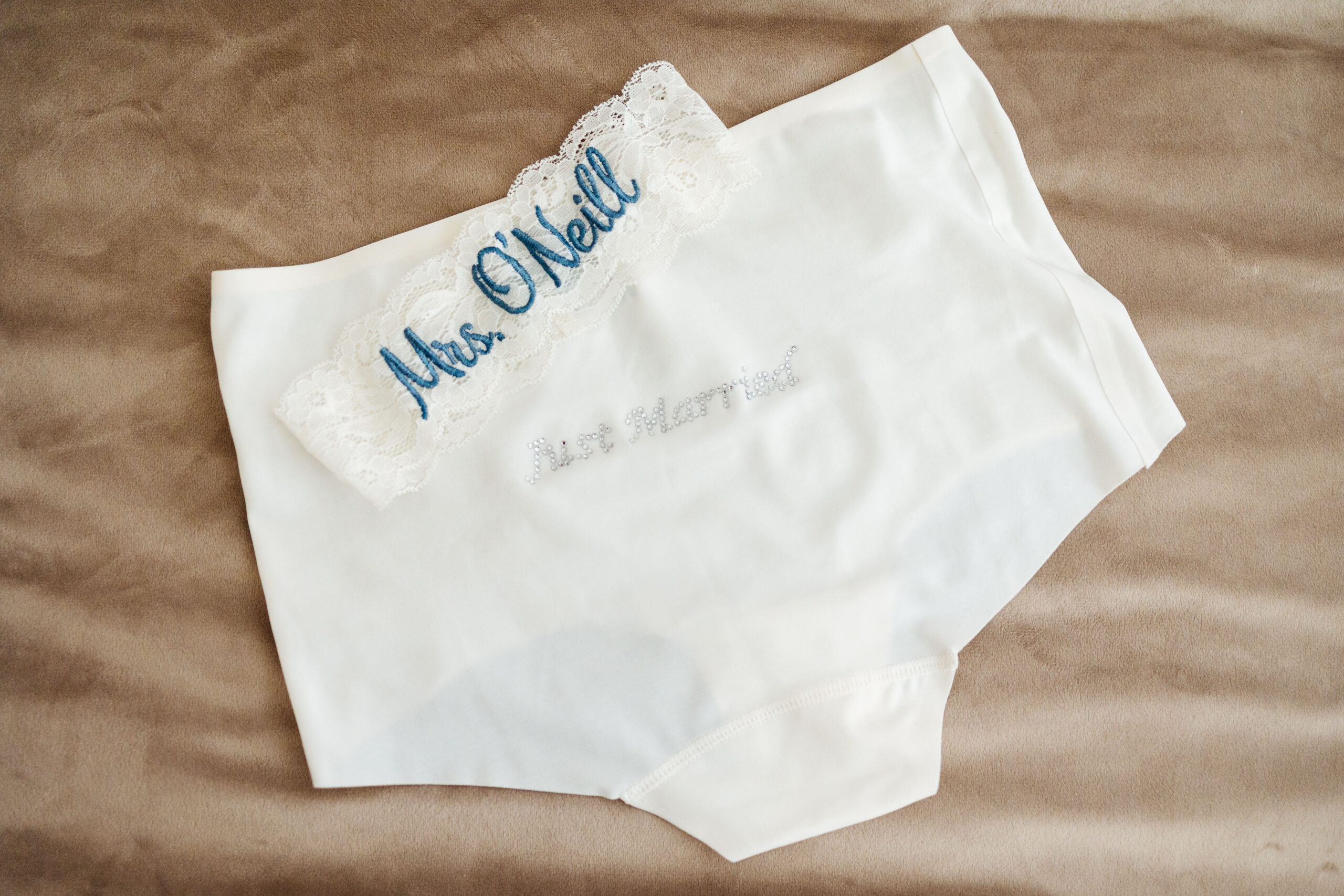 A pair of white pants that have "Just Married" on in jewells and a white, lacey garter that has Mrs O'Neill embroidered on.