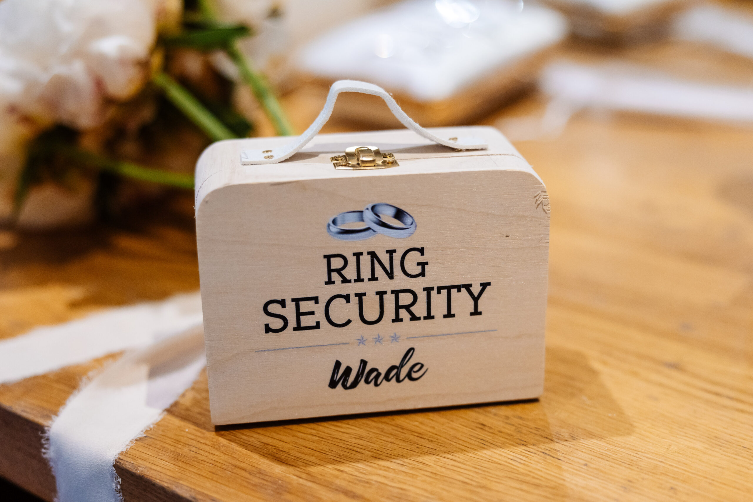 A wooden box with Ring Security and Wade written on it. It has a small white handle and is on a table.