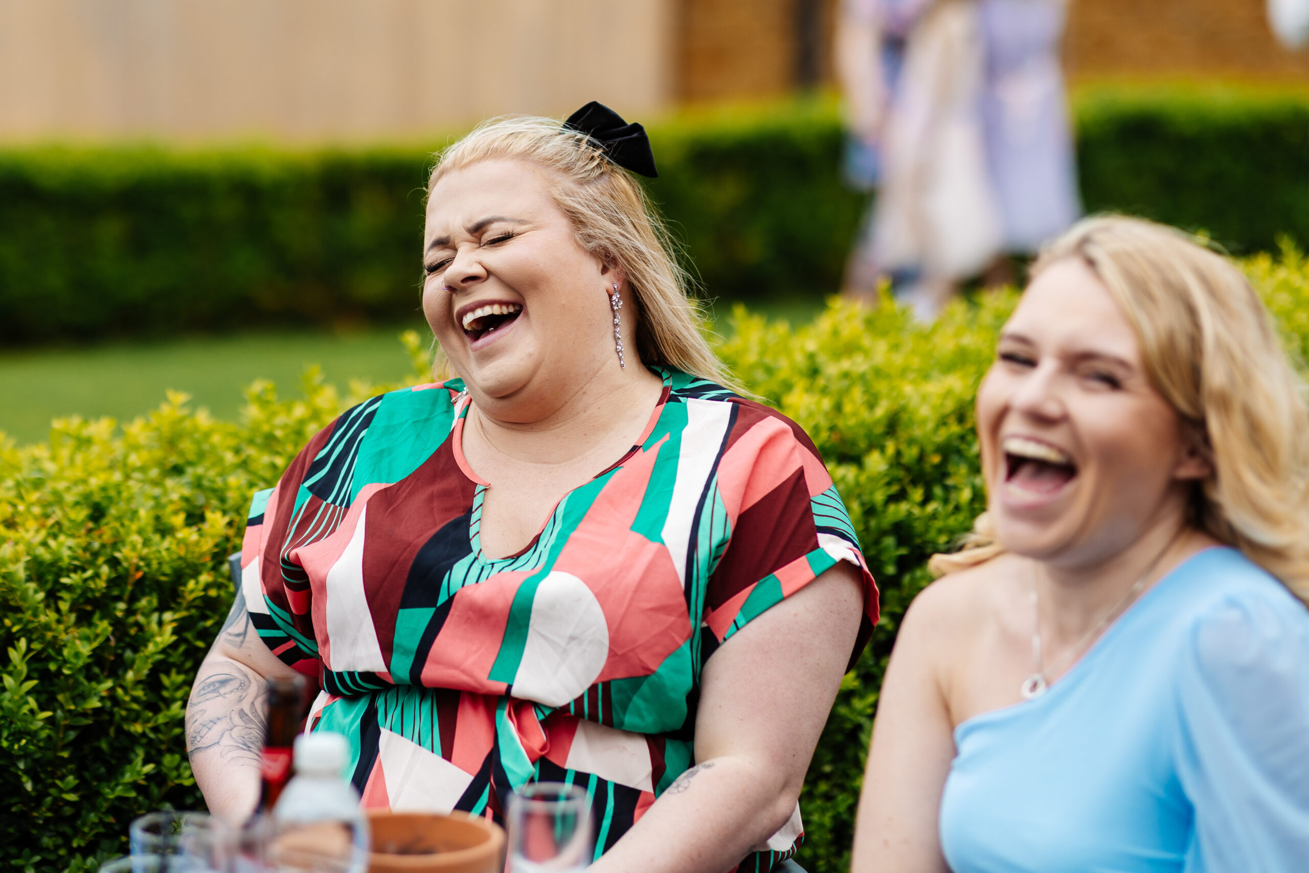 Two wedding guests laughing with their mouths open having a great time.