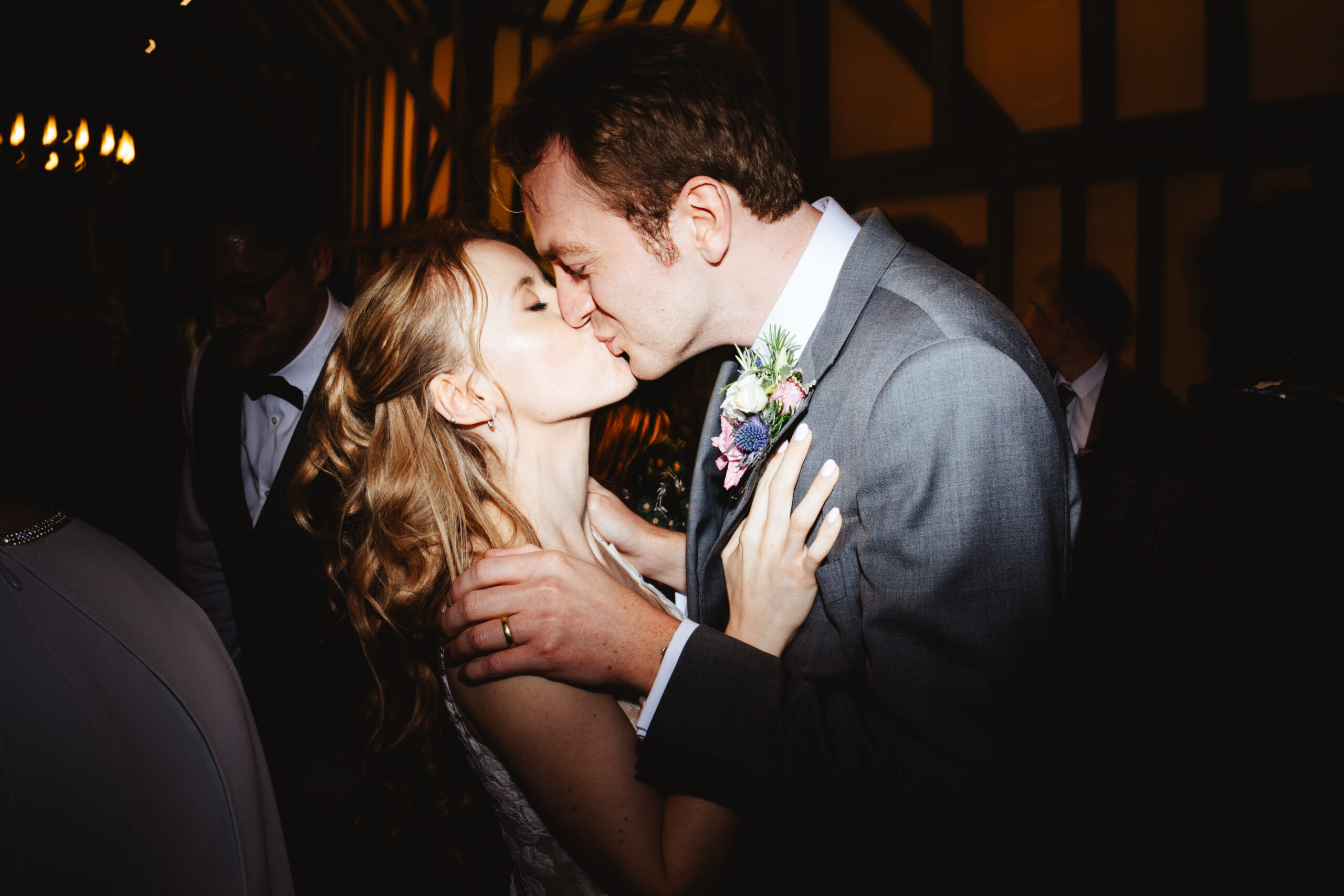 A bride and groom kissing. They are on the dancefloor, surrounded by friends and family.