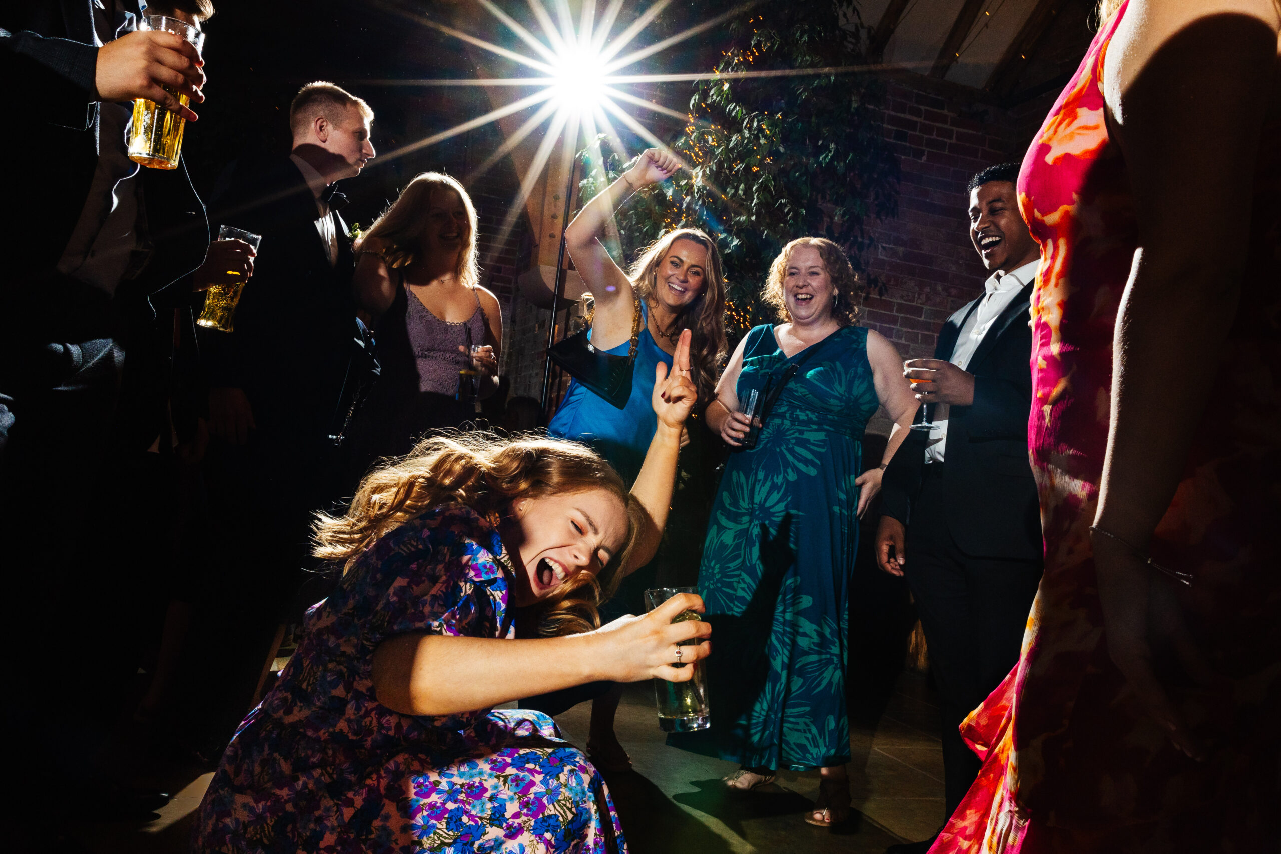 Guests partying the night away. One of the guests has her hand in the air and is kneeling down towards the floor as she is dancing.