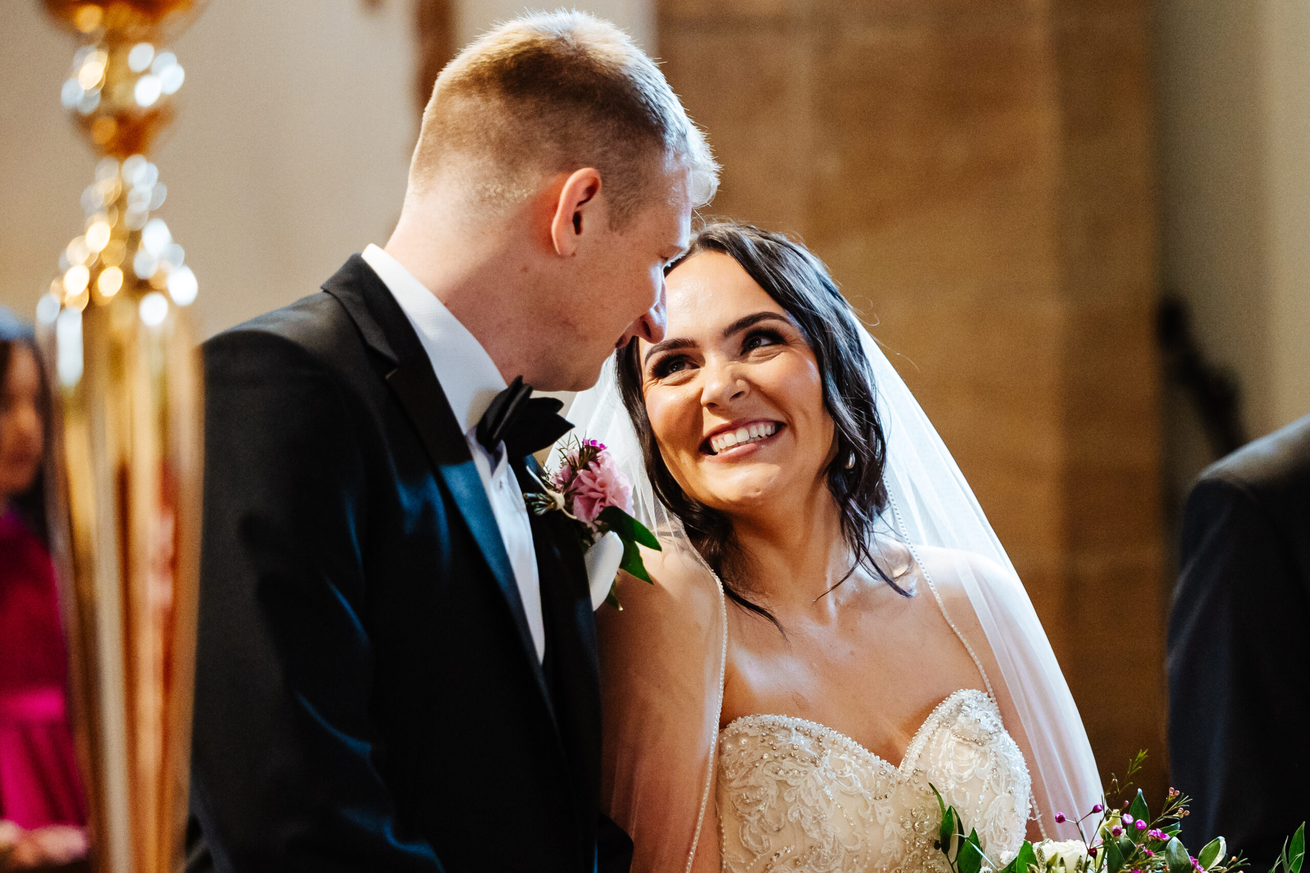 The bride and groom at the top of the alter. They are looking at each other and smiling.