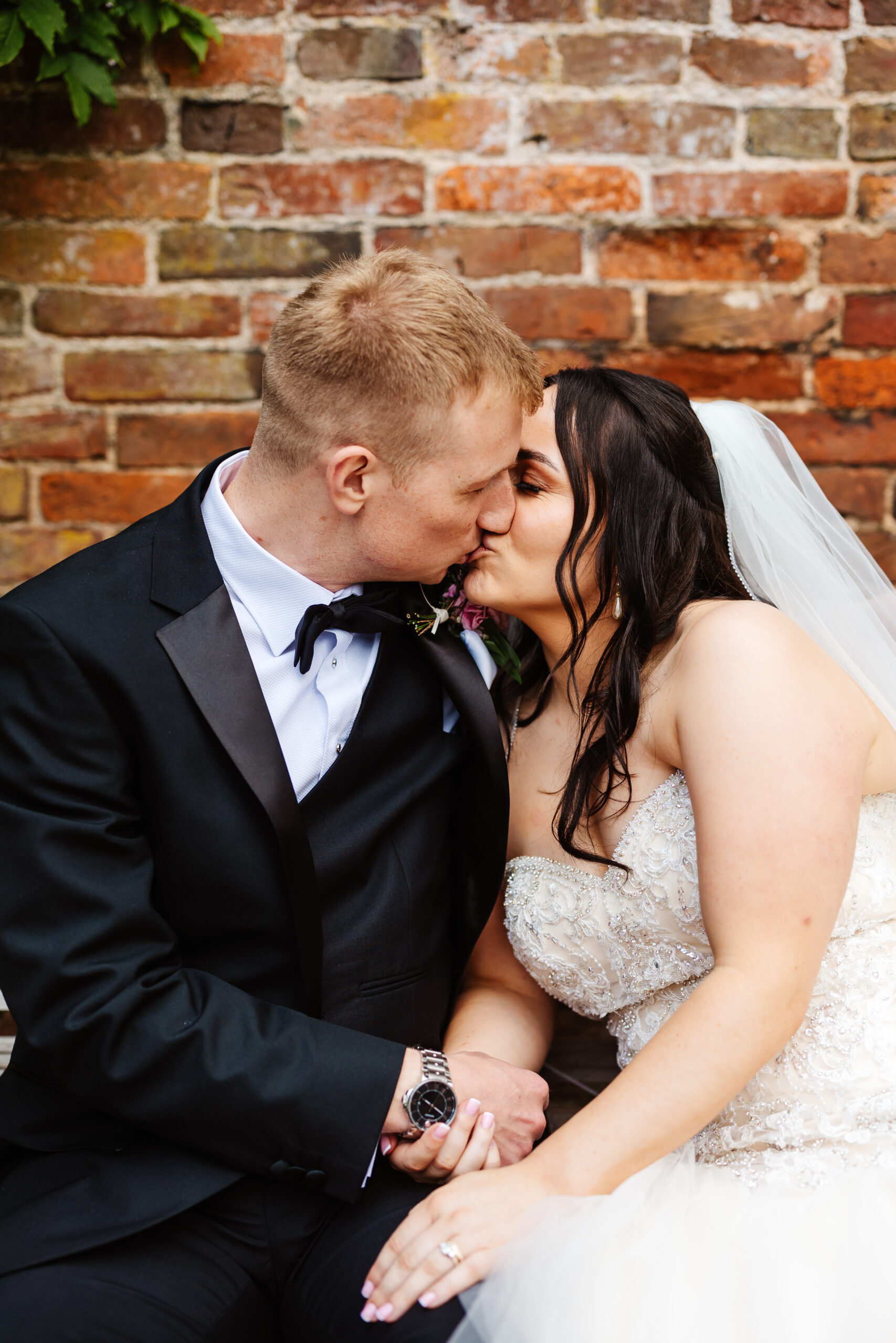 A photo of the bride and groom kissing and holding hands.