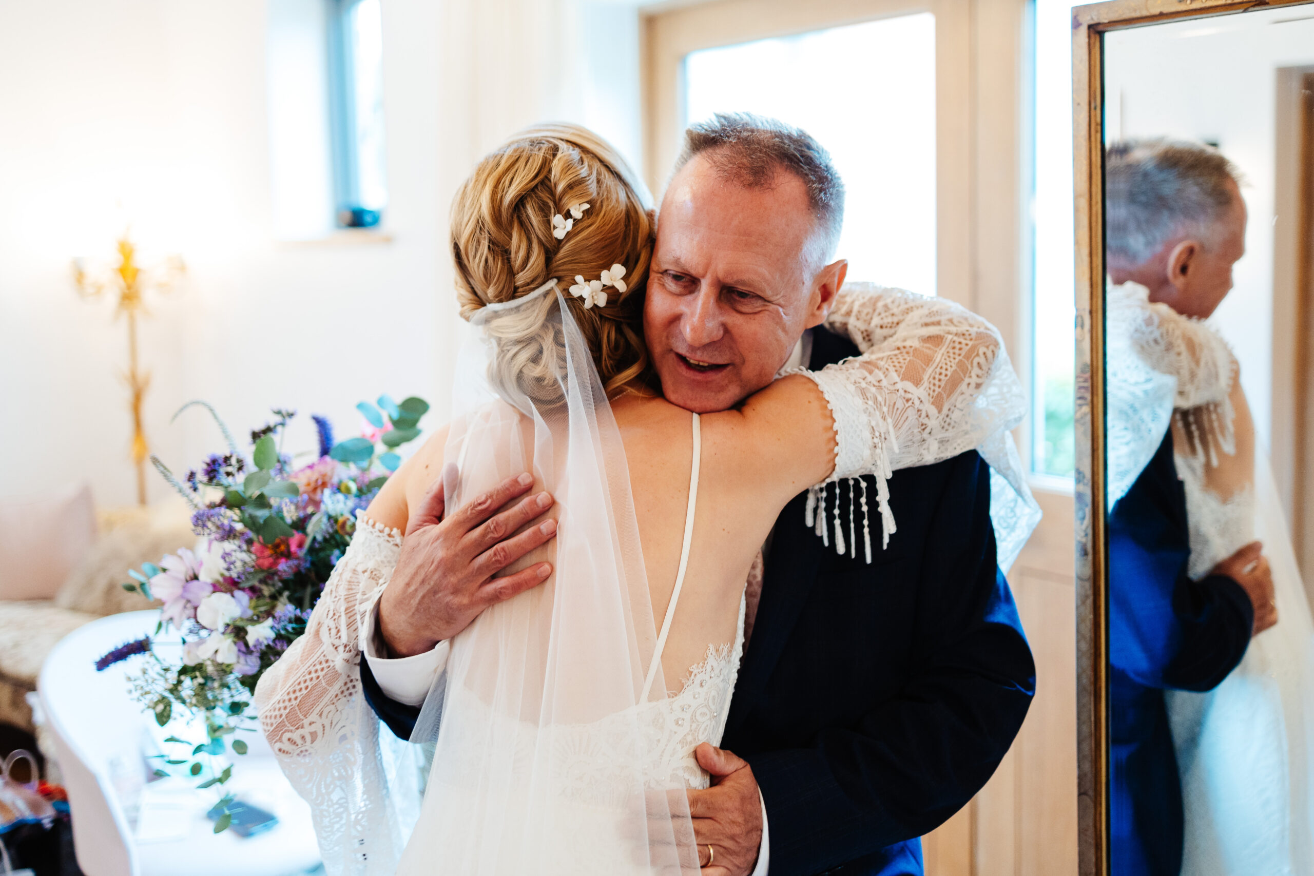 The father of the bride and the bride hugging after he has seen her in her dress for the first time.