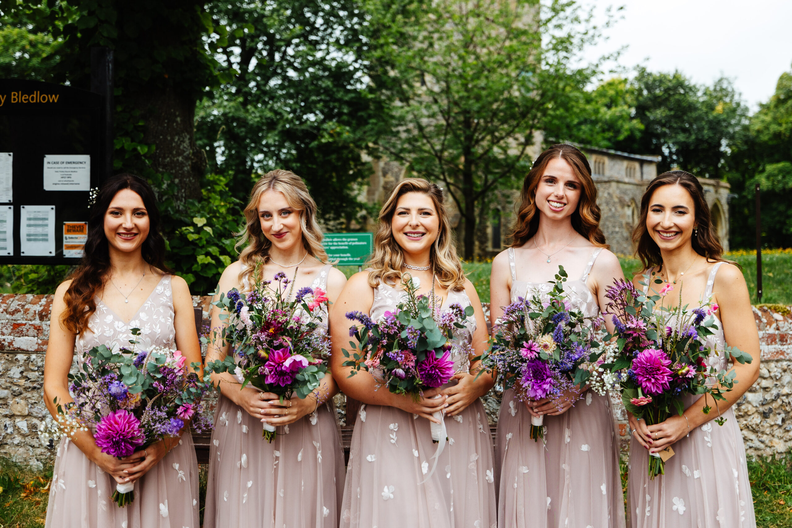 A photo of the bridesmaids holding their bouquets infront of the church where the bride and groom are about to get married.