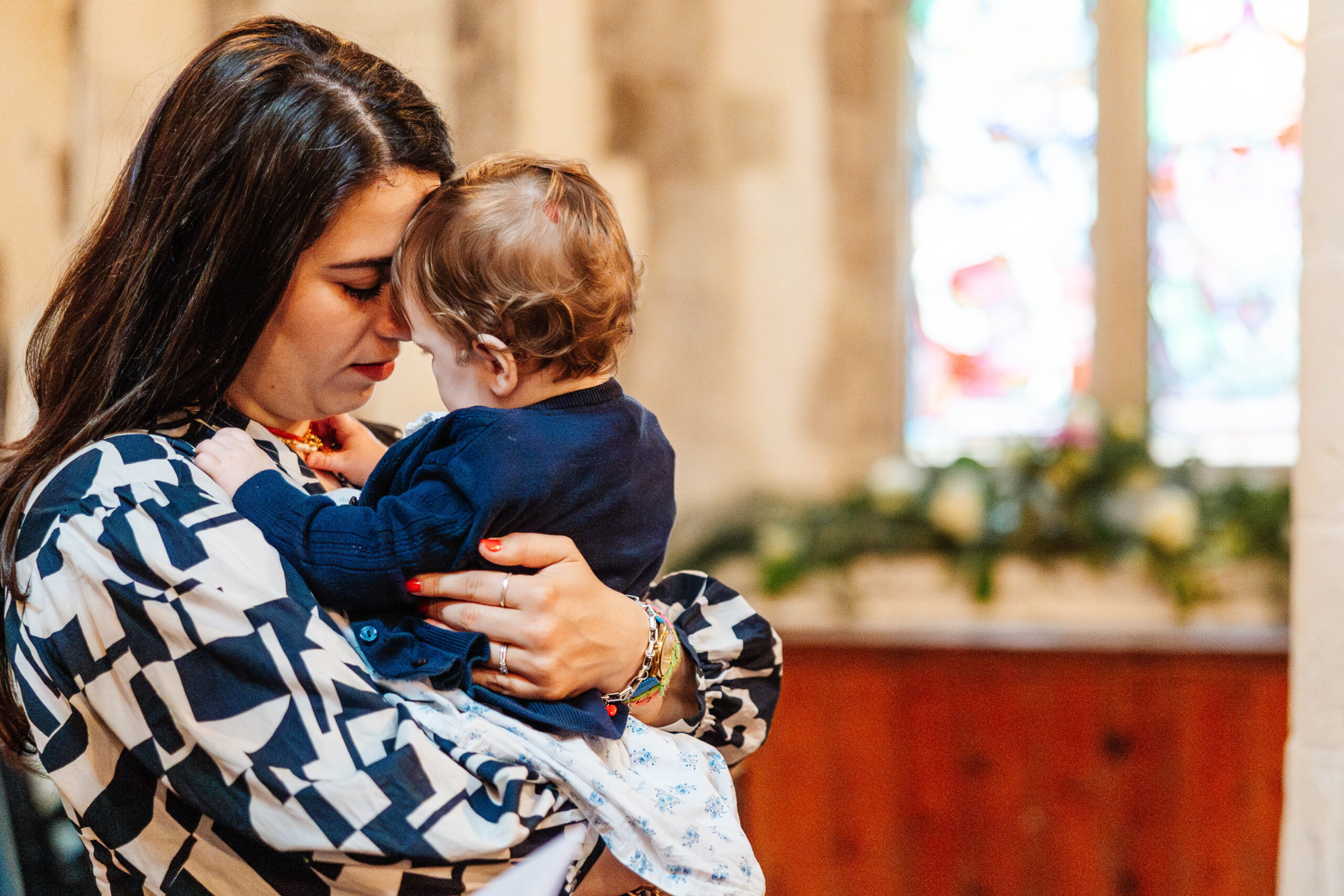 A photo of a mother holding her baby in her arms. They have their heads pressed together.