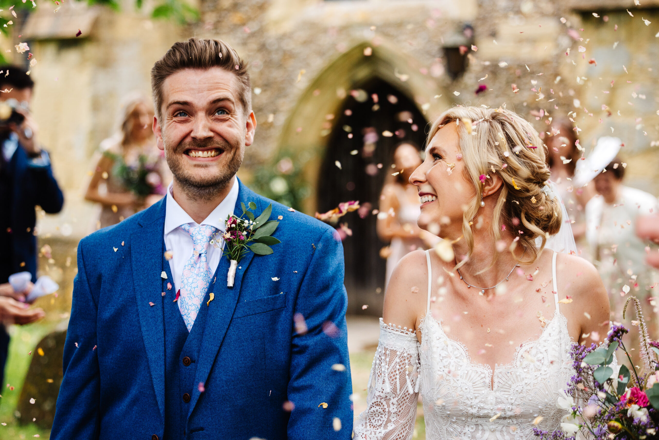 A shot of the bride and groom smiling with confetti falling down.