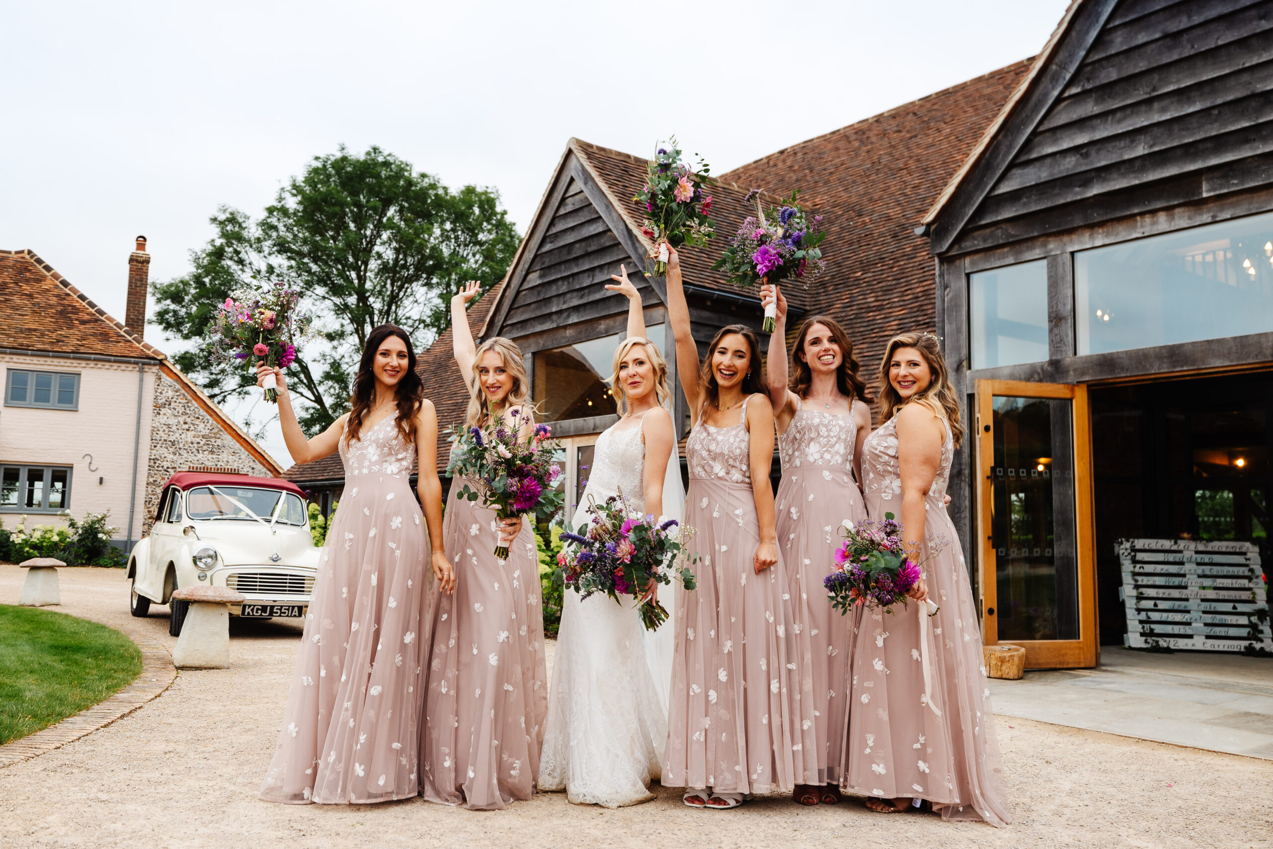 A group shot of the bridesmaids. They have their hands in the air and are smiling and having a good time.