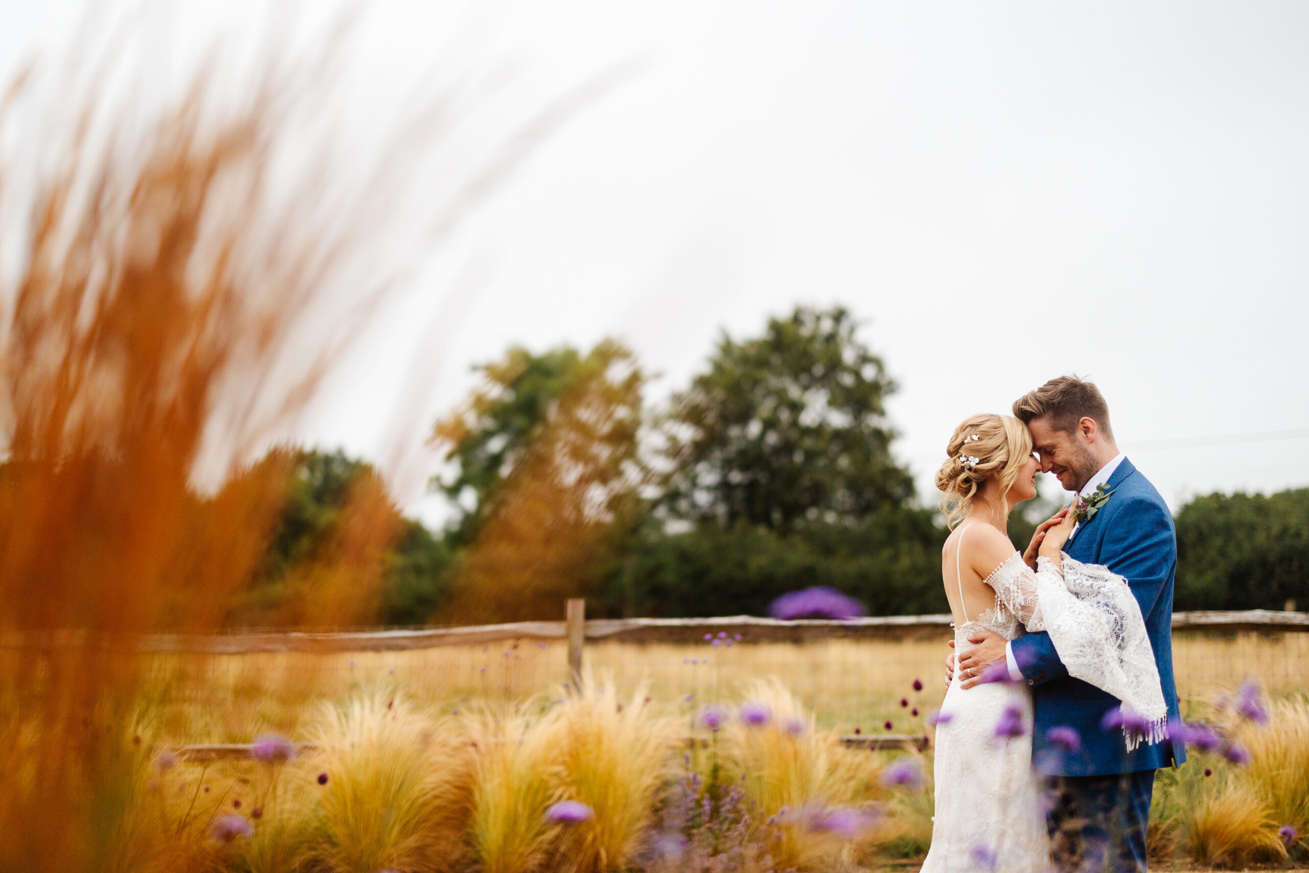 The bride and groom in a cornfield outside. They are embracing each other and looking at one another.