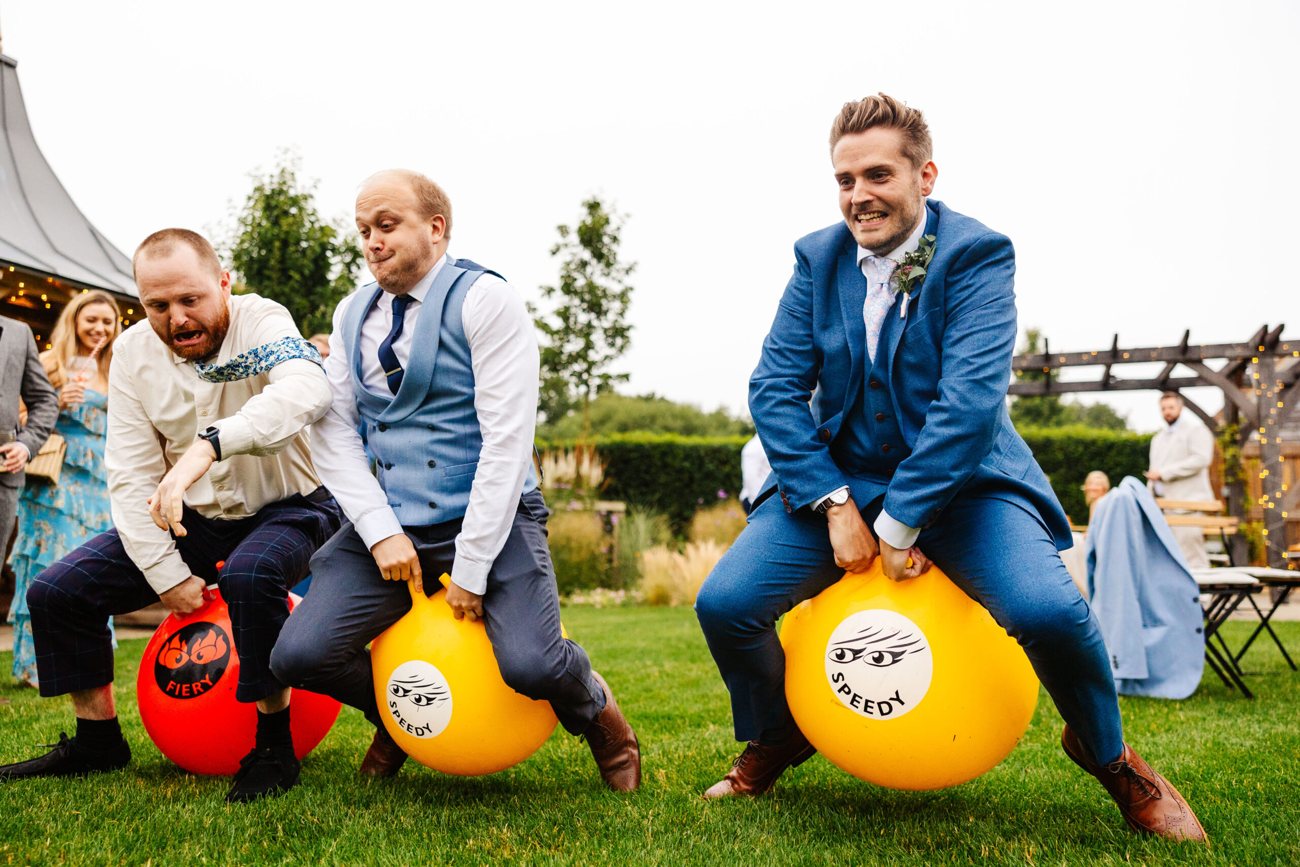 The groom and some guests on space hoppers. They are bouncing in the air and look like they are having a great time.