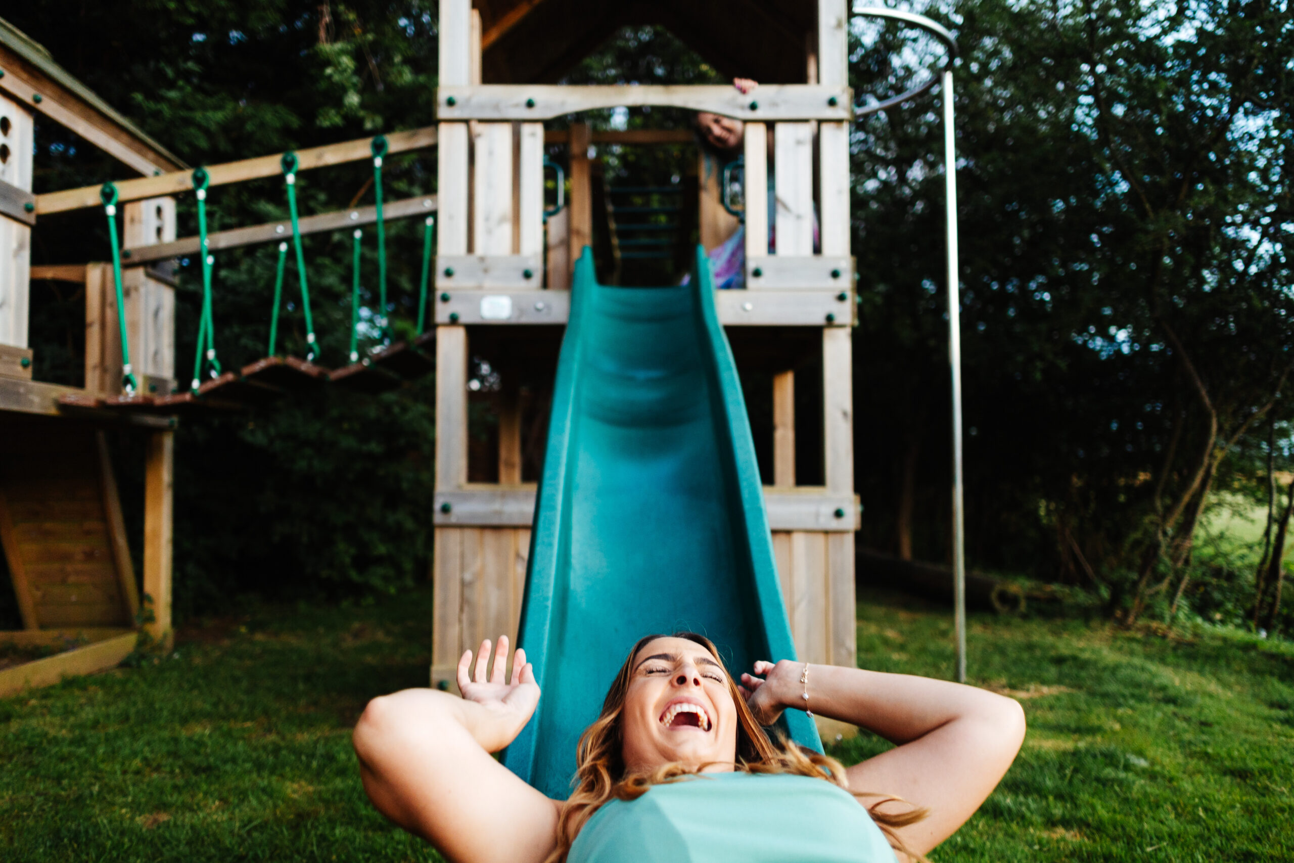 A guest who has gone down a child's slide. She is lying down with her hands above her head and she is smiling.