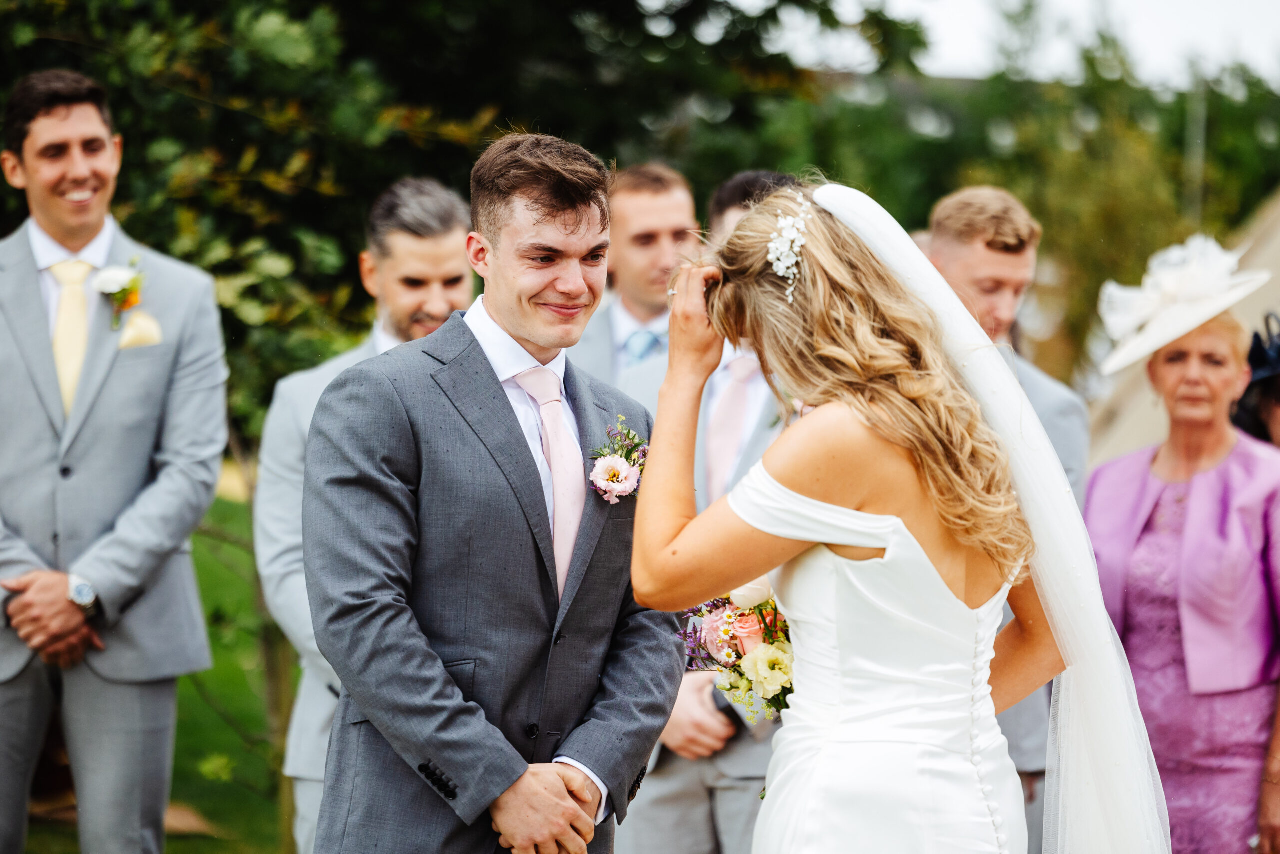 The bride and groom at the top of the alter. The bride is sorting her hair out and the groom is looking at her smiling and crying in happiness.