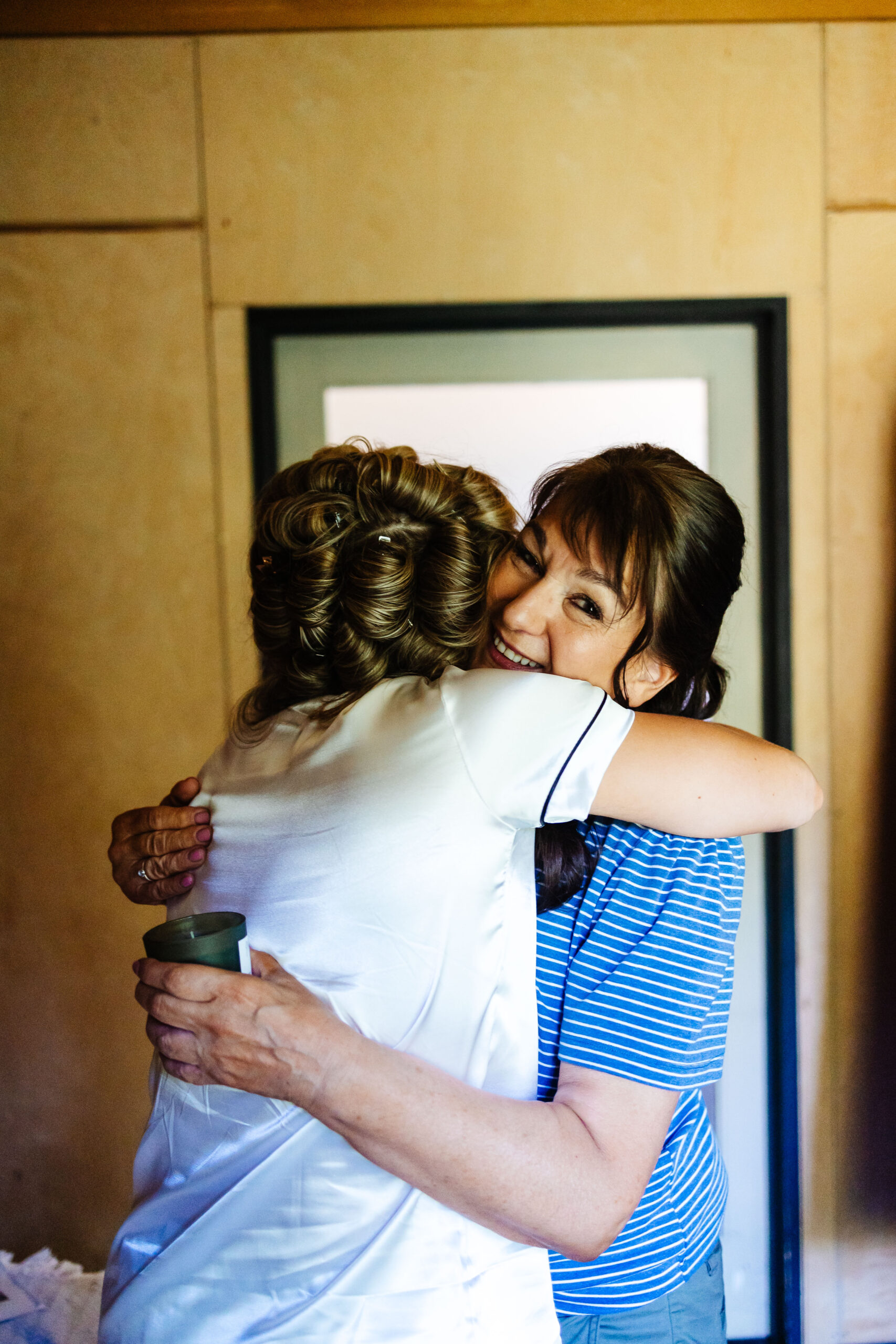 The bride's mum and the bride sharing a hug. The mum has a candle in her hand, a gift from her daughter.