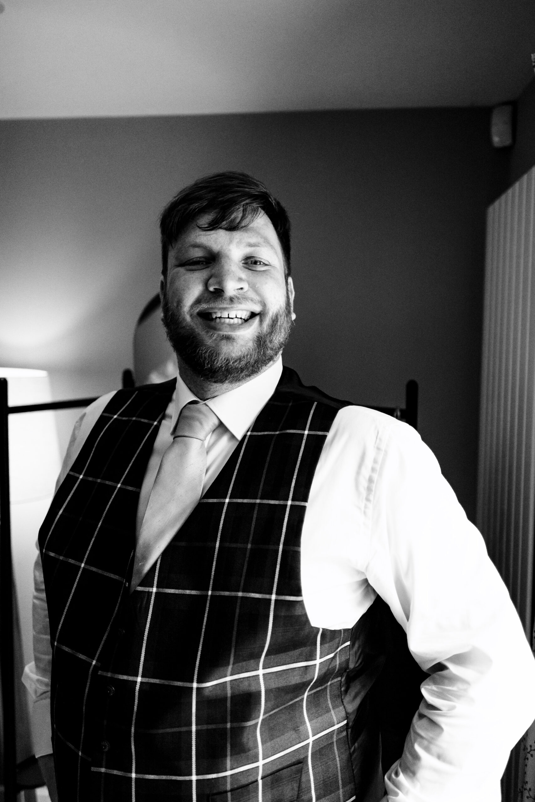 A black and white image of the groom. He is smiling and looks very happy with himself.