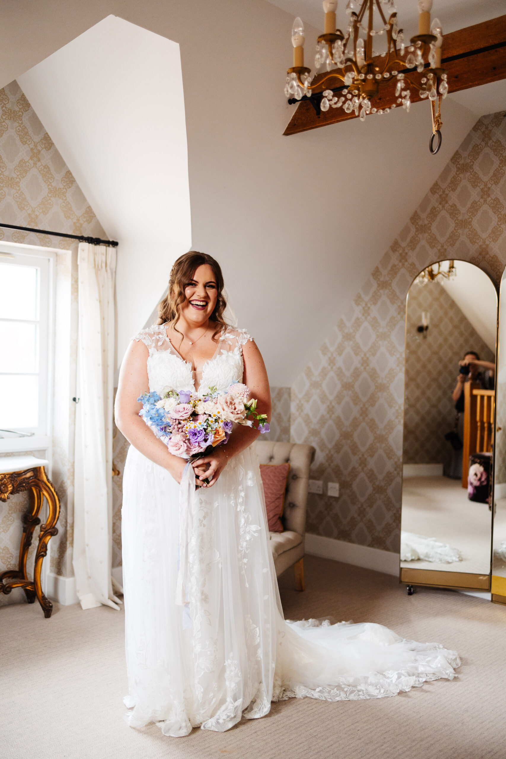 The bride in her dress and with her flowers. She is smiling and looks very happy.