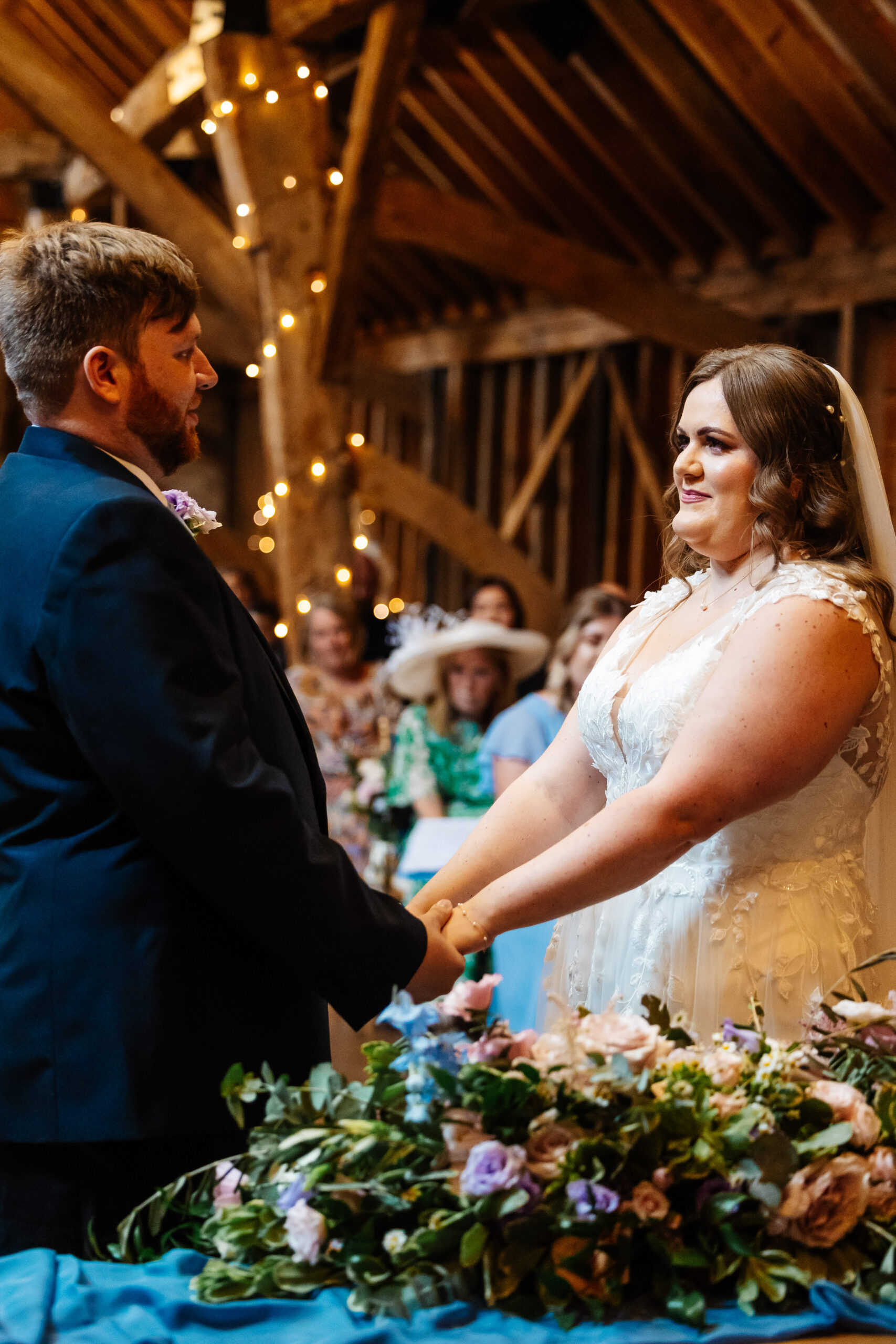 A portrait image of the bride and groom. They are holding hands and looking at each other. They are smiling.